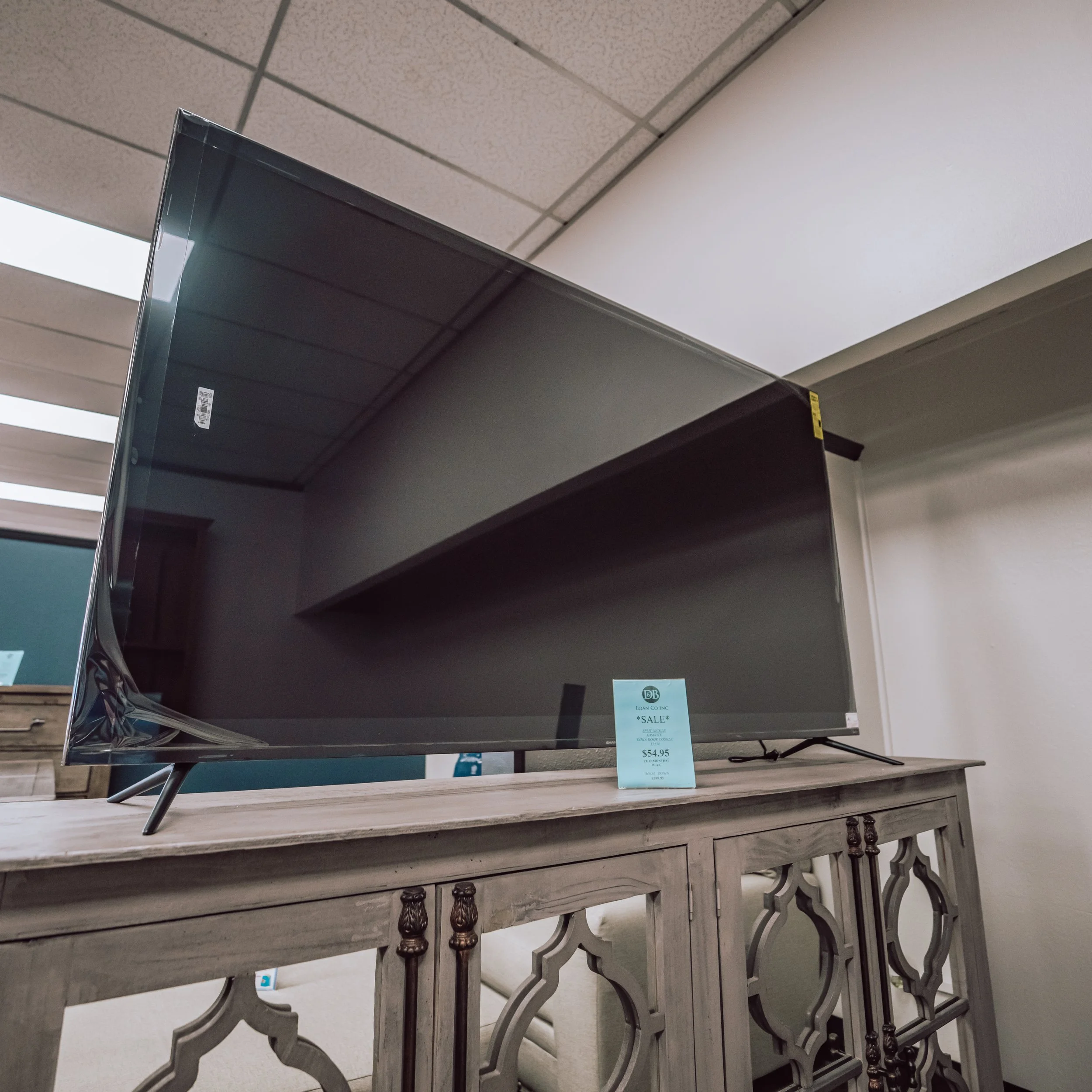 Flat-screen TV displayed on a wooden console table in a store