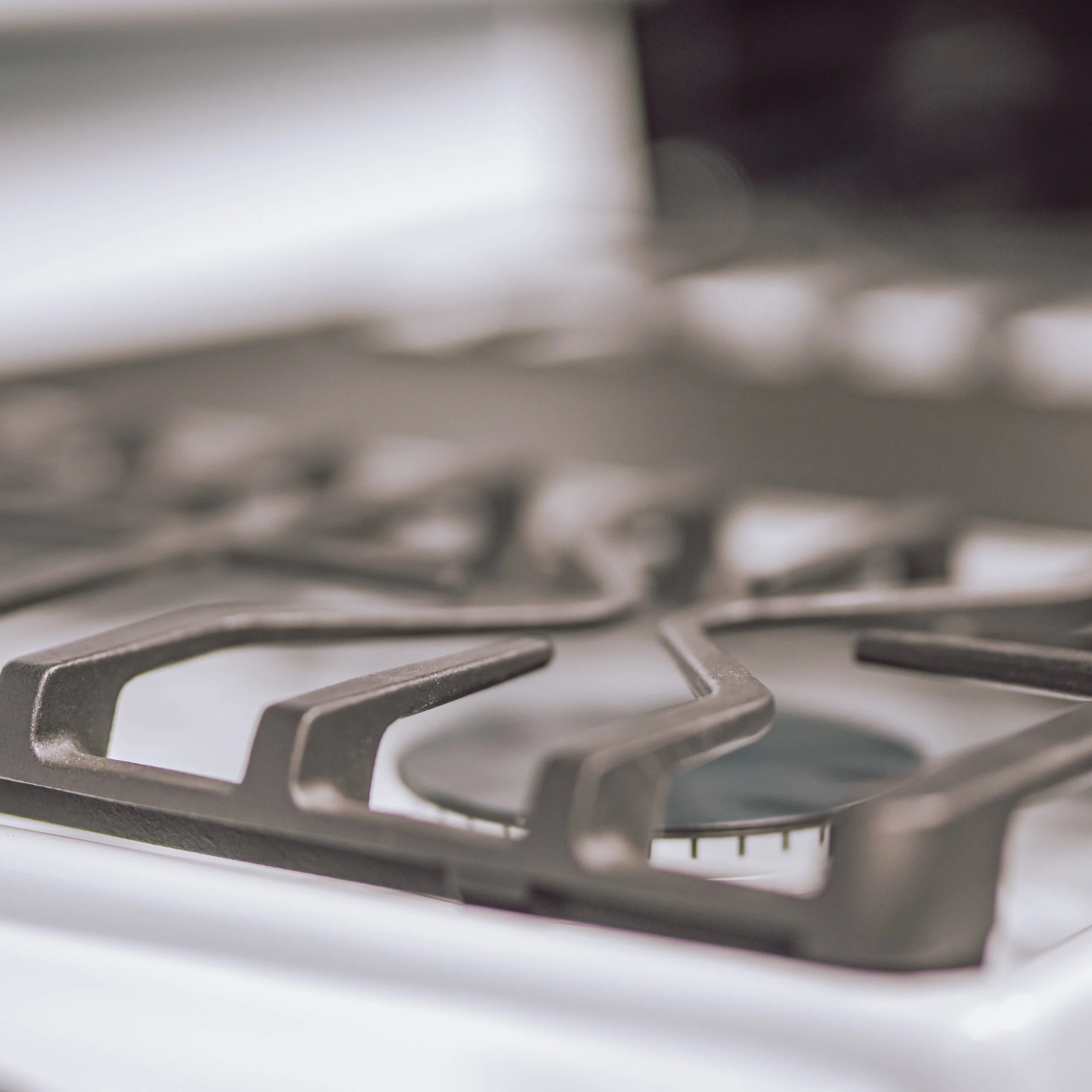 Close-up photograph of a gas stove burner with metal grate and cast iron support.