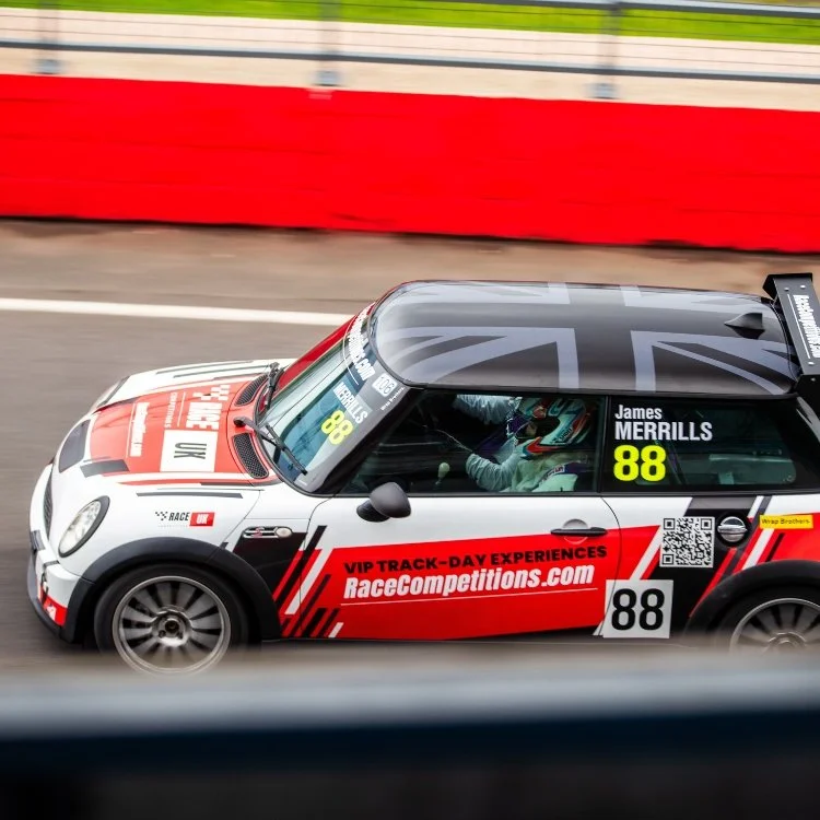 Race car with the number 88 driven by James Merrills on a track, showing green grass and red and white barriers in the background.