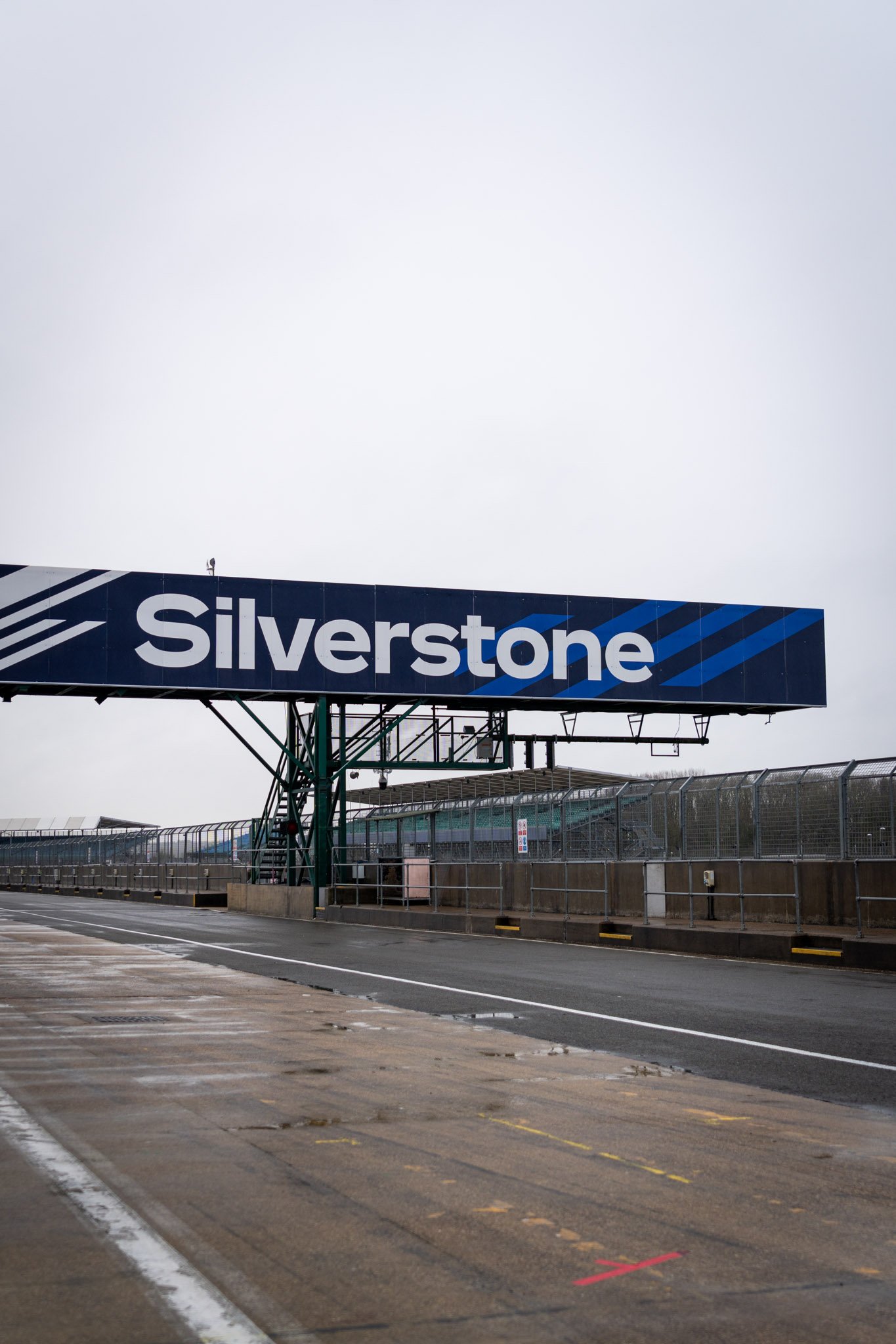 An image of the Silverstone light gantry with the words 'SILVERSTONE' on a blue background over the race track.