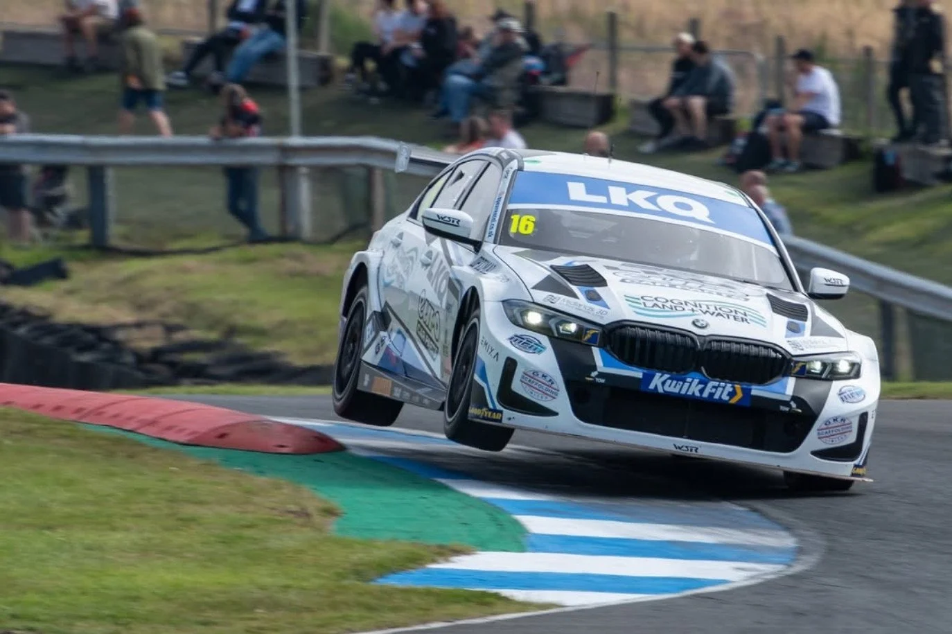 A white BMW racing at knockhill race track in Scotland, in the British Touring Car Championship (BTCC)