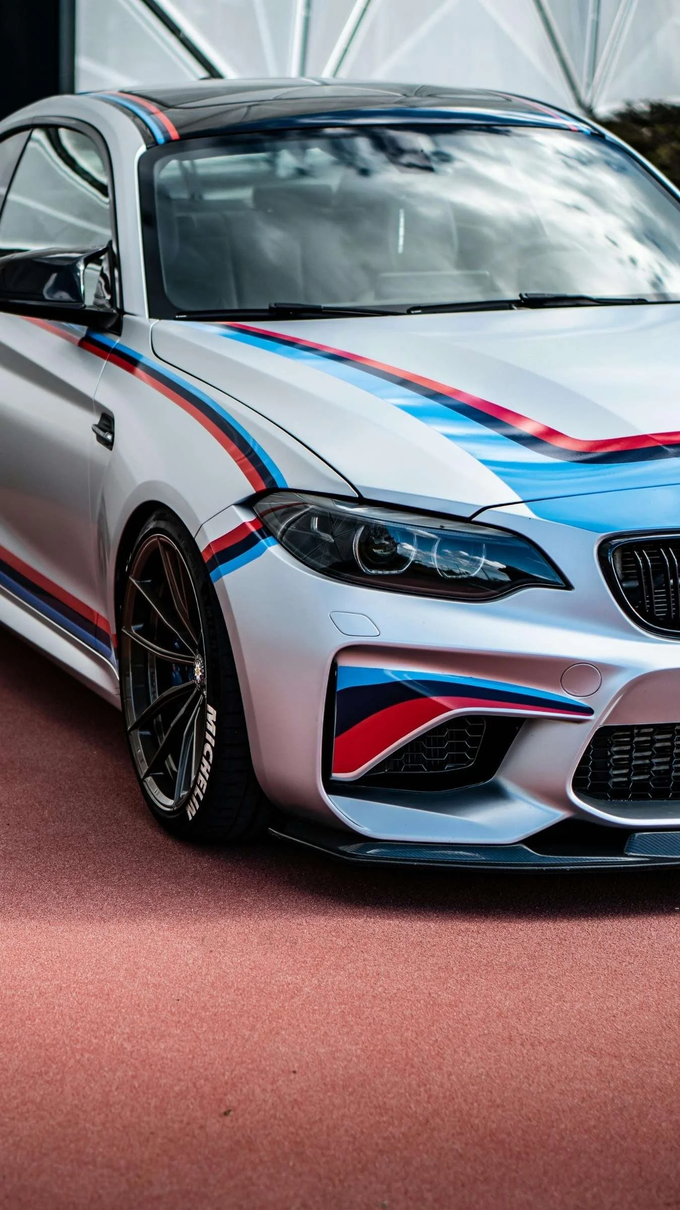 A silver BMW M2 Competition parked in pit lane at a track day.