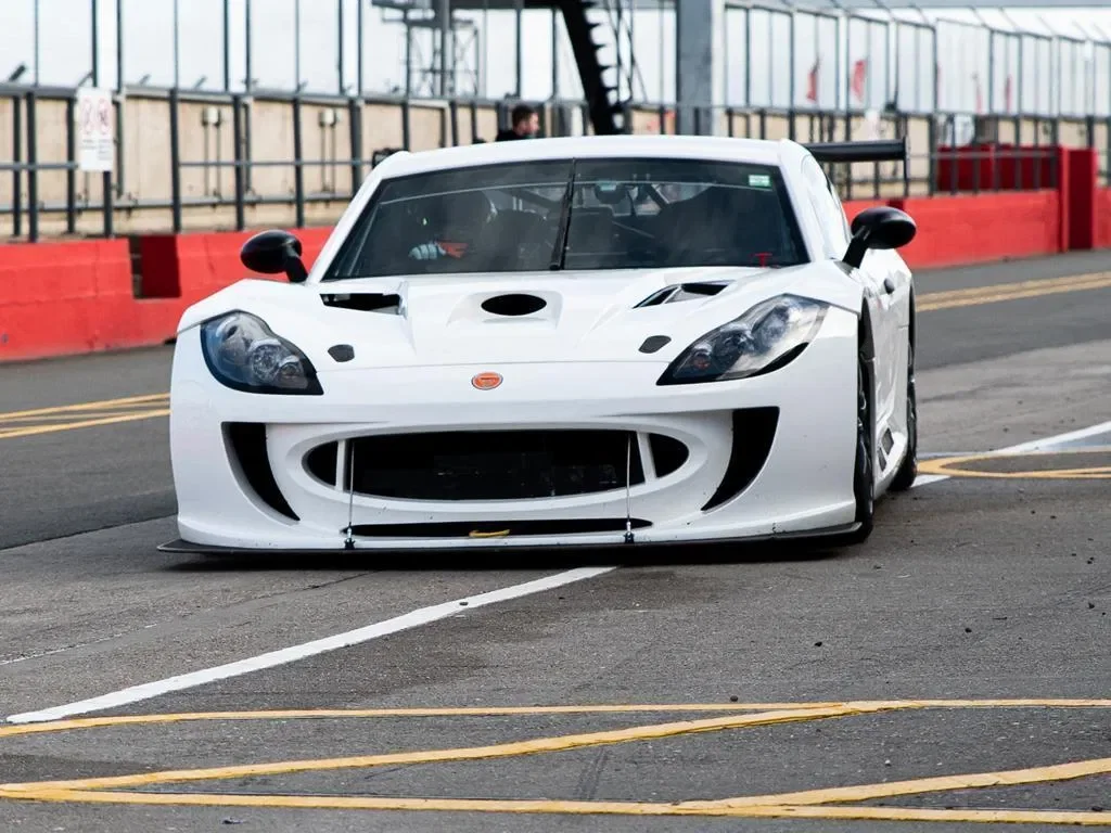 A white race car on a drag strip, with a low front end and aerodynamic design.