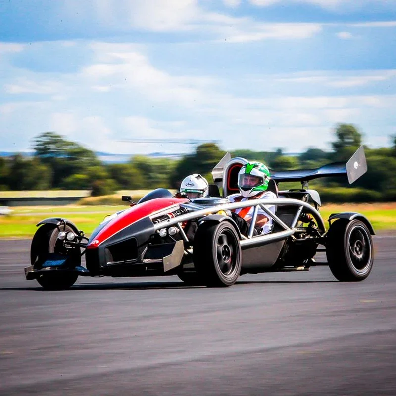 A red Ariel Atom racing down a runway during a corporate driving experience