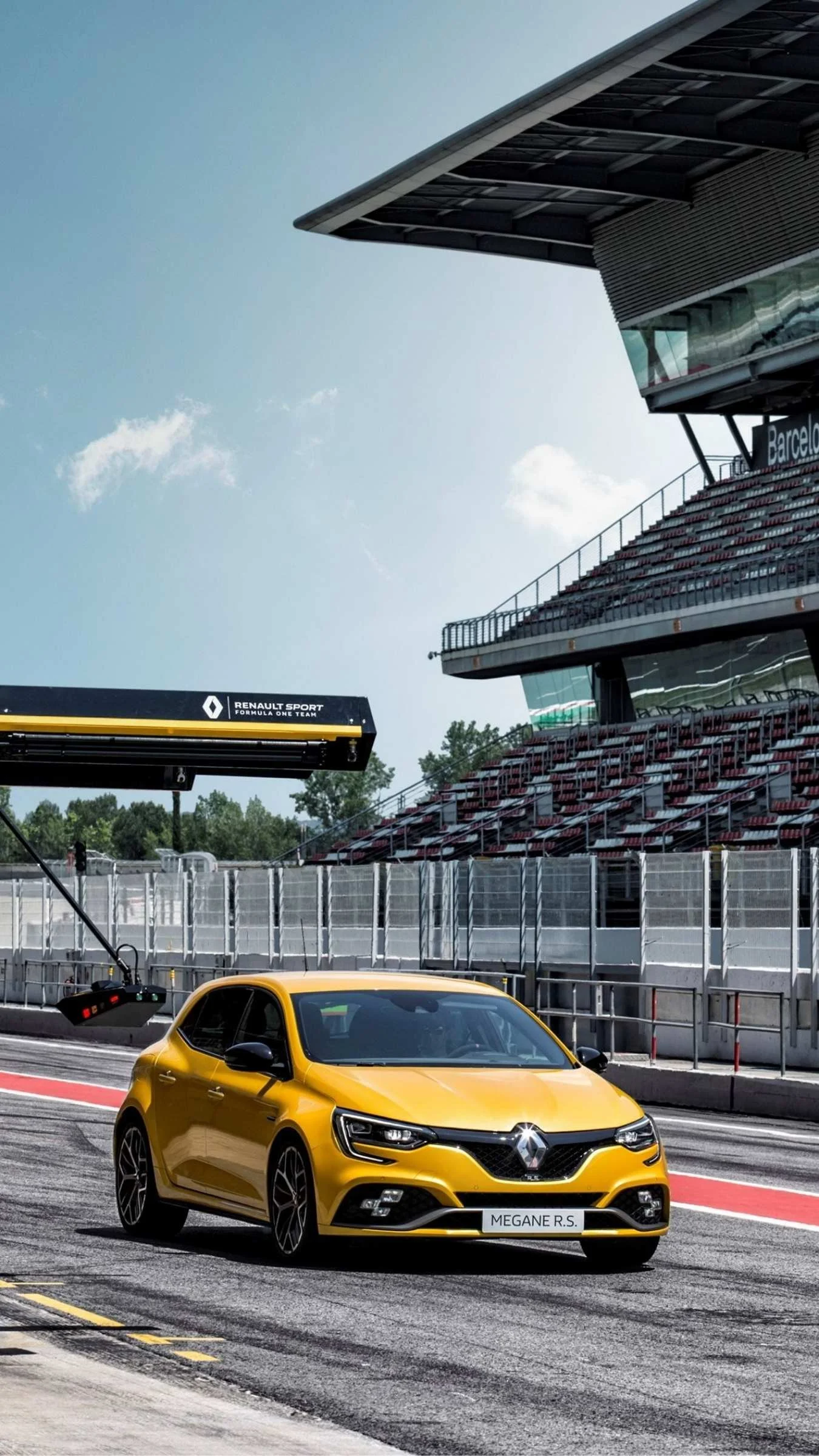 A Yellow Renault Megane RS in the pit lane on a sunny track day at the Barcelona F1 track