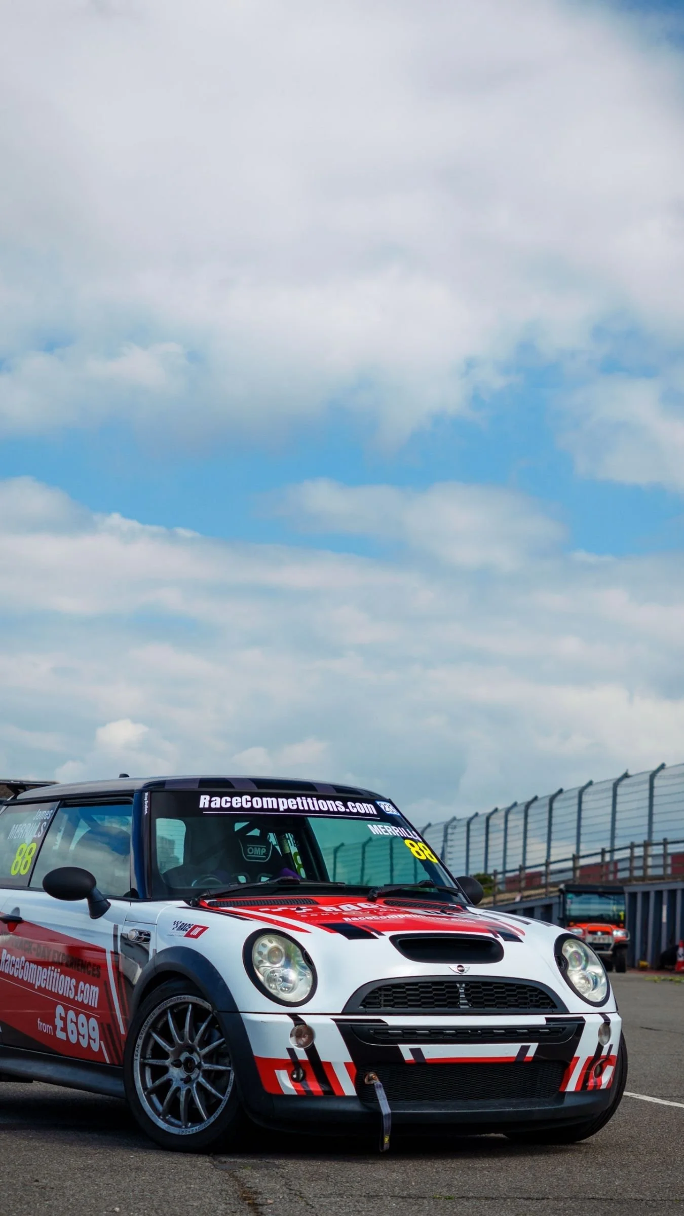 A red and white MINI Cooper-S race car parked in the paddock at Donington Park, Derby, on a sunny track day