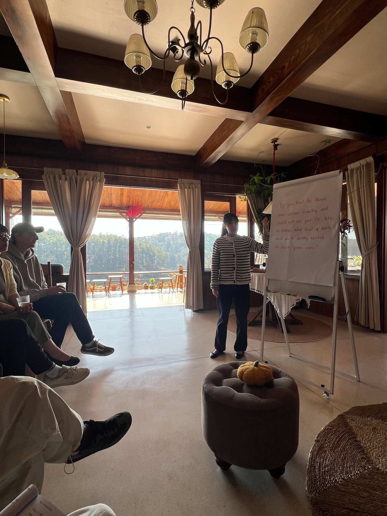 A woman sitting on a rock outdoors, writing in a notebook, surrounded by nature with fog and trees in the background.