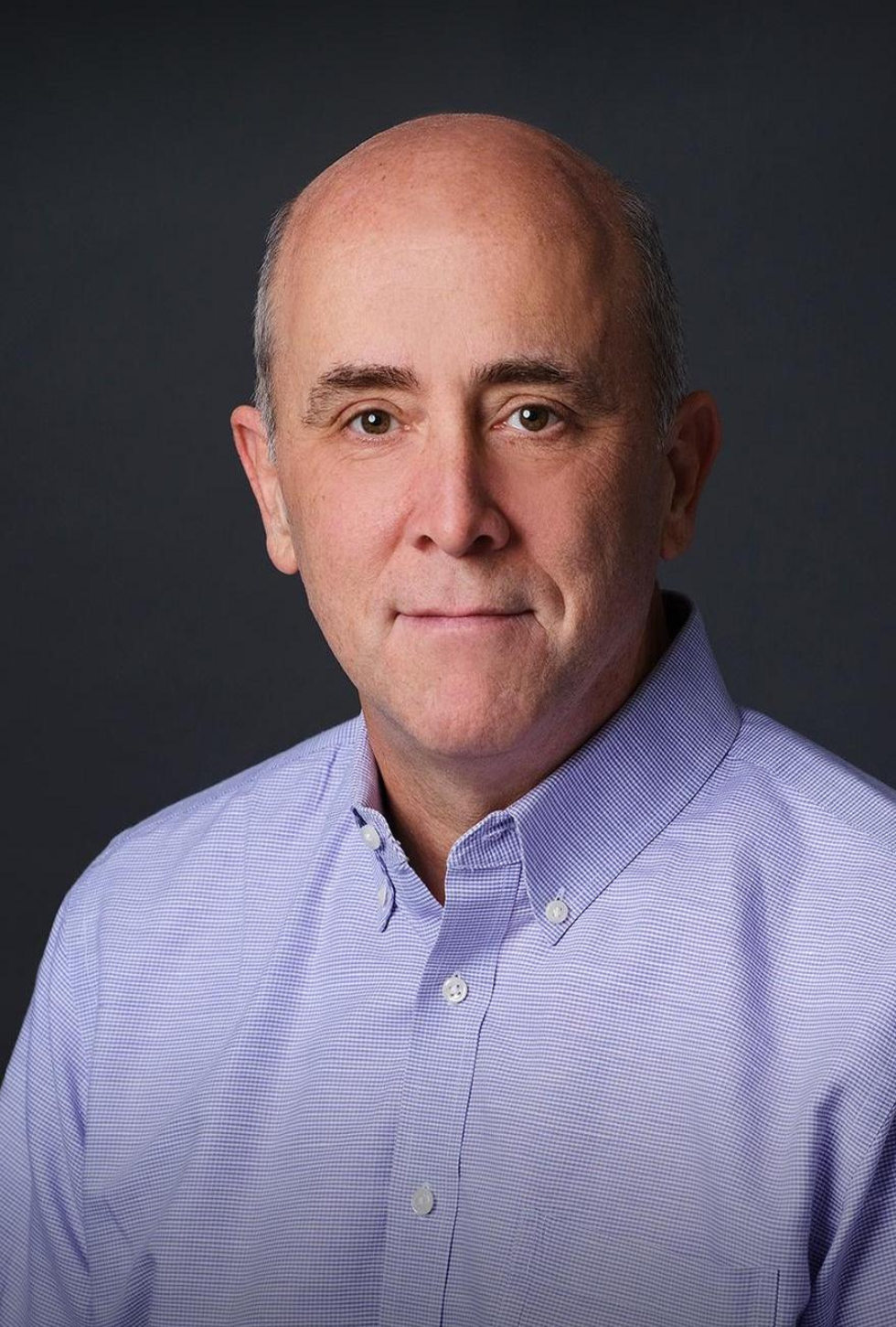 Will West, CEO, in a professional headshot wearing a light purple button-down shirt, against a dark background.