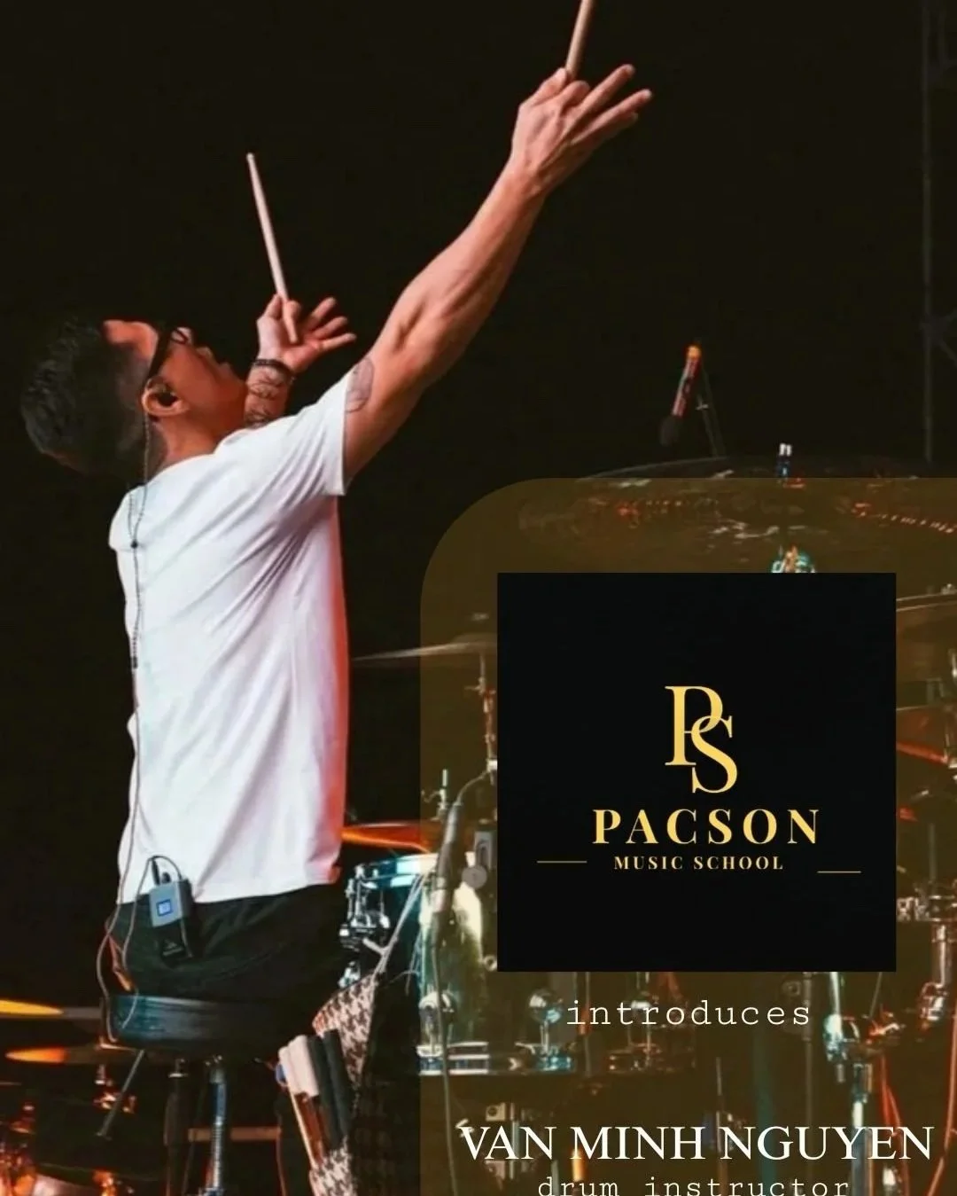 A person conducting an orchestra with a baton, wearing glasses and a white t-shirt, featuring a tattoo on the right arm, in a dark setting with a grand piano and a logo for Pacson Music School.