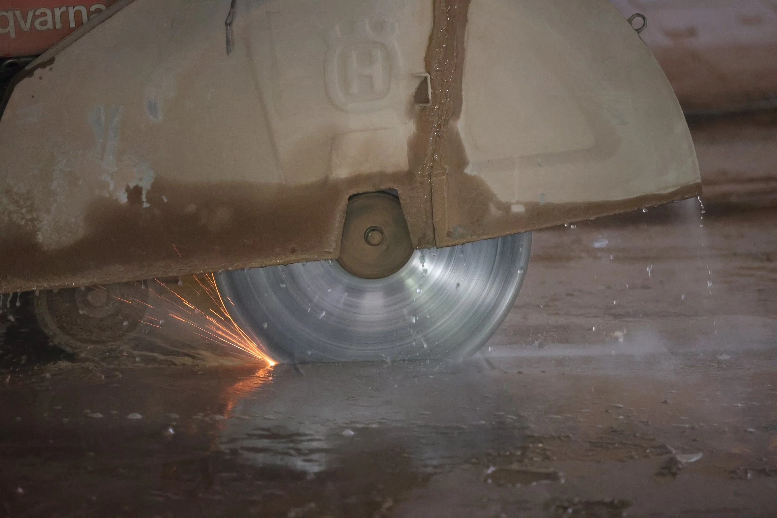 A close-up of a saw blade cutting through a piece of metal with sparks flying from the cutting process.