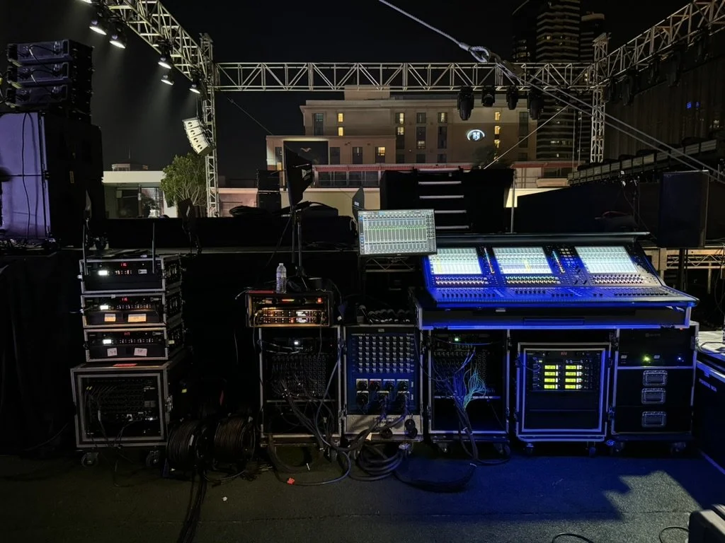 A group of musicians and singers performing on stage in front of an audience, with stage lights shining down.