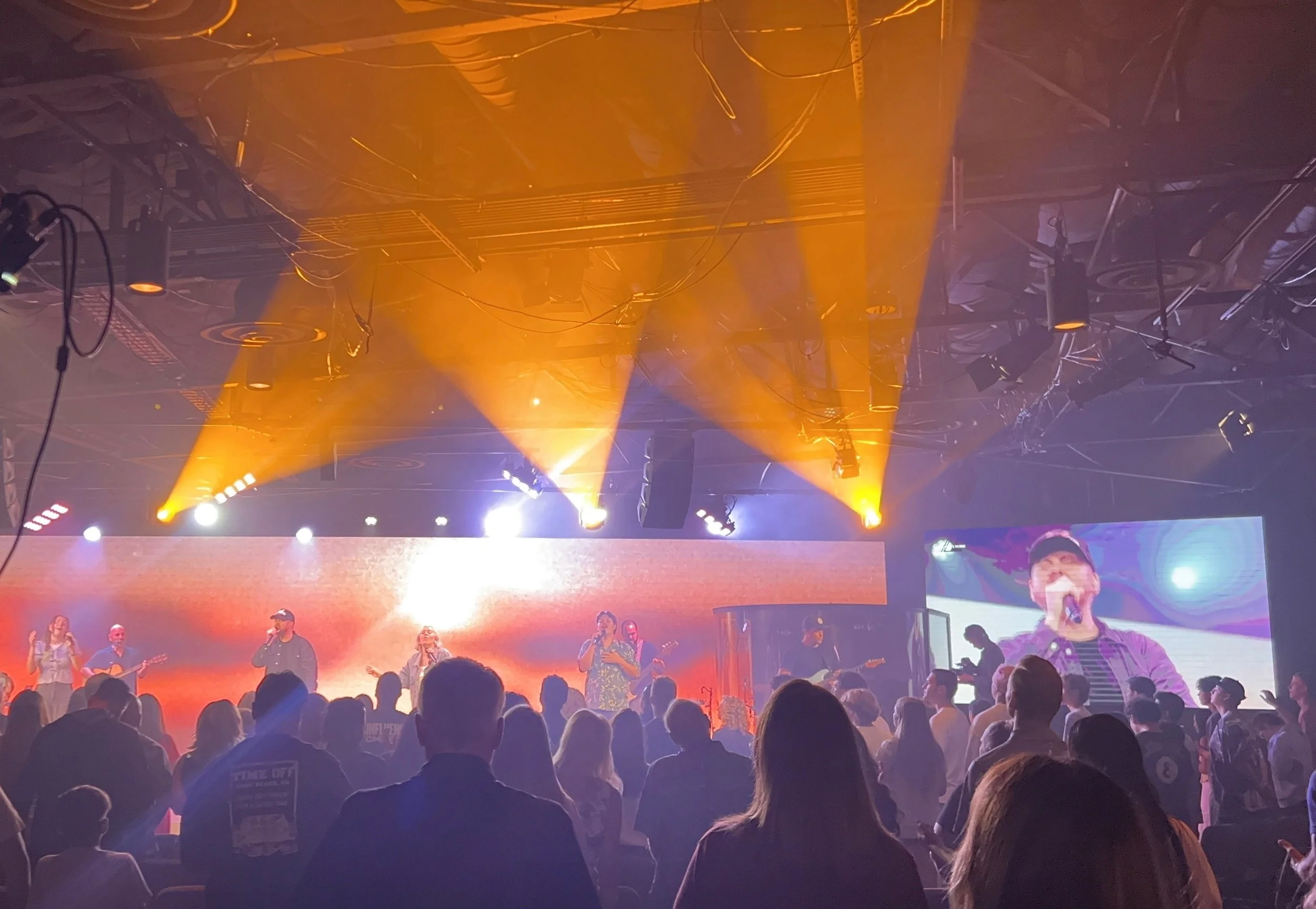 Stage lighting with red and white spotlights and beams illuminating the dark stage ceiling.