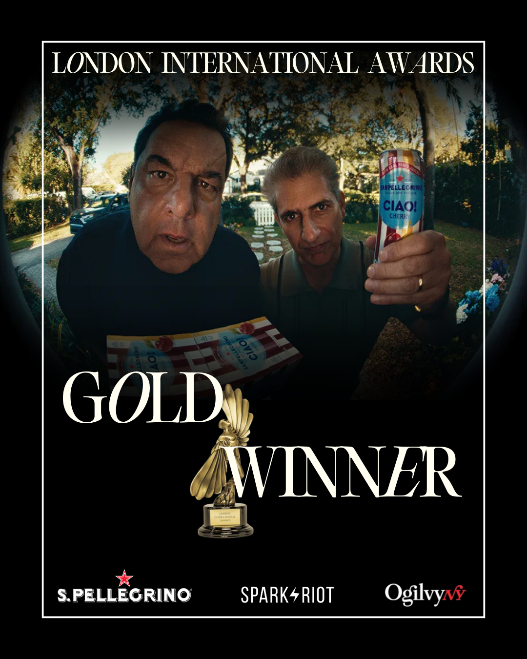 Two men at the London International Awards event, one holding a can of S. Pellegrino sparkling water, with a backdrop of trees and cars, and a gold trophy with the text GOld Winner.