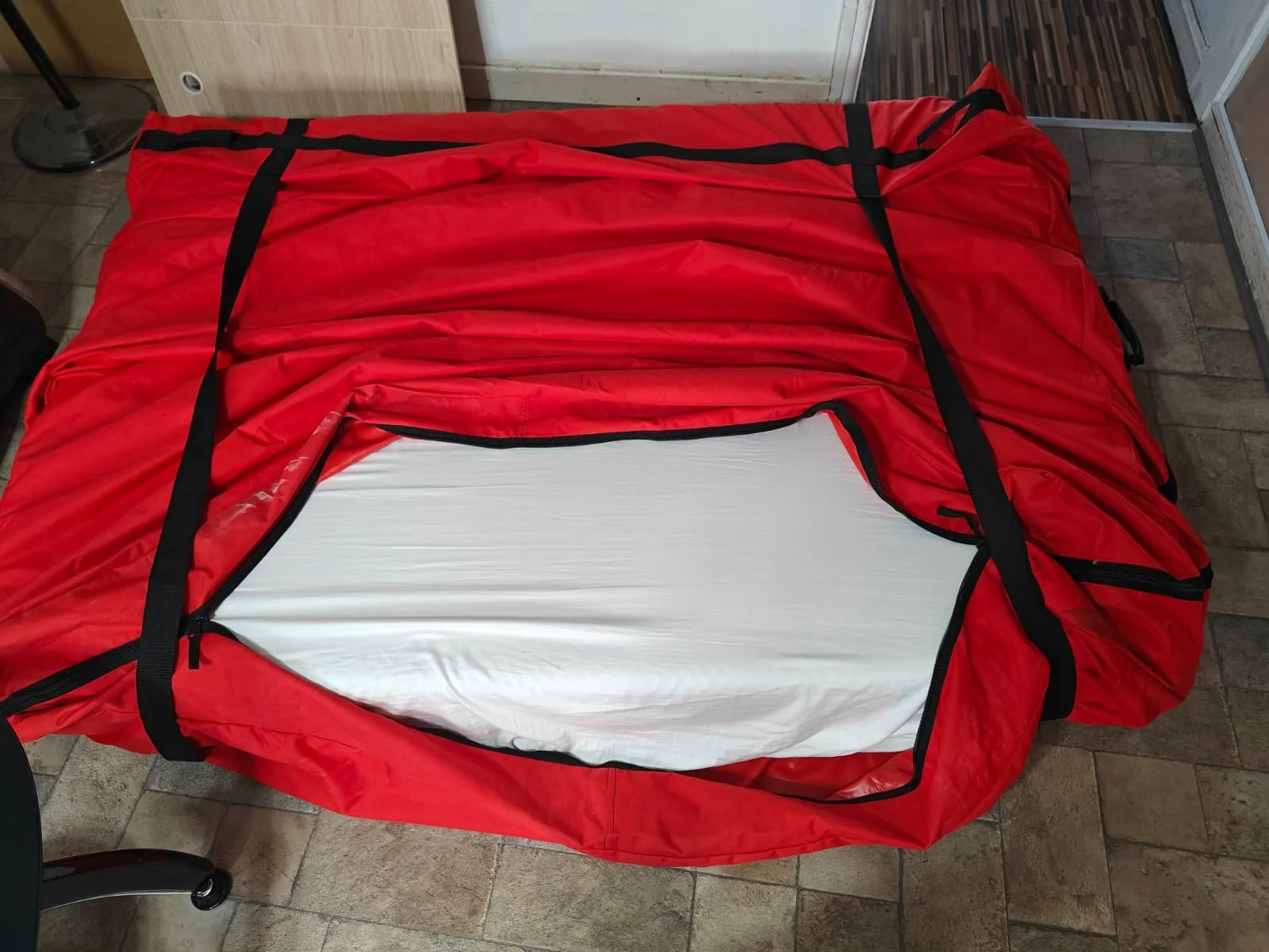 A red and black ripstop duffel bag with a zipper opening revealing a white interior lining.