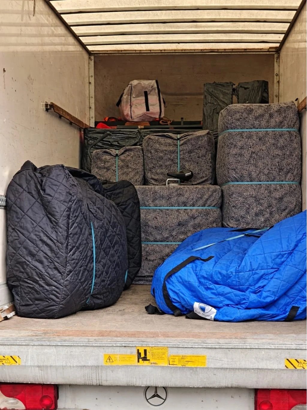 The back of a moving truck filled with packed luggage, bags, and boxes.