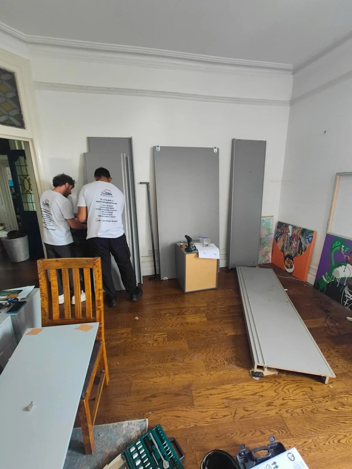 2 removal men from ready to go house movers and removals working on taking apart a wardrobe