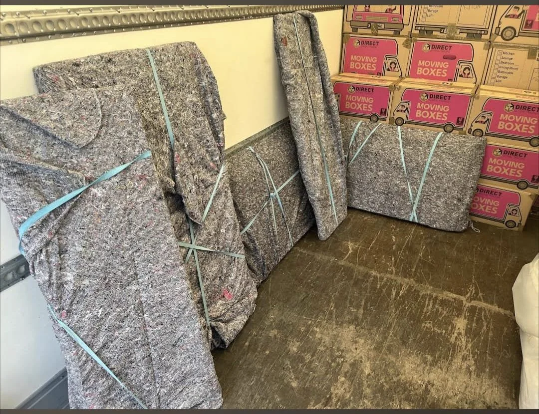 Large furniture items wrapped using premium removal blankets and secured with moving straps, with boxes carefully stacked behind. This protective loading method helps ensure a safe and damage-free house move.
