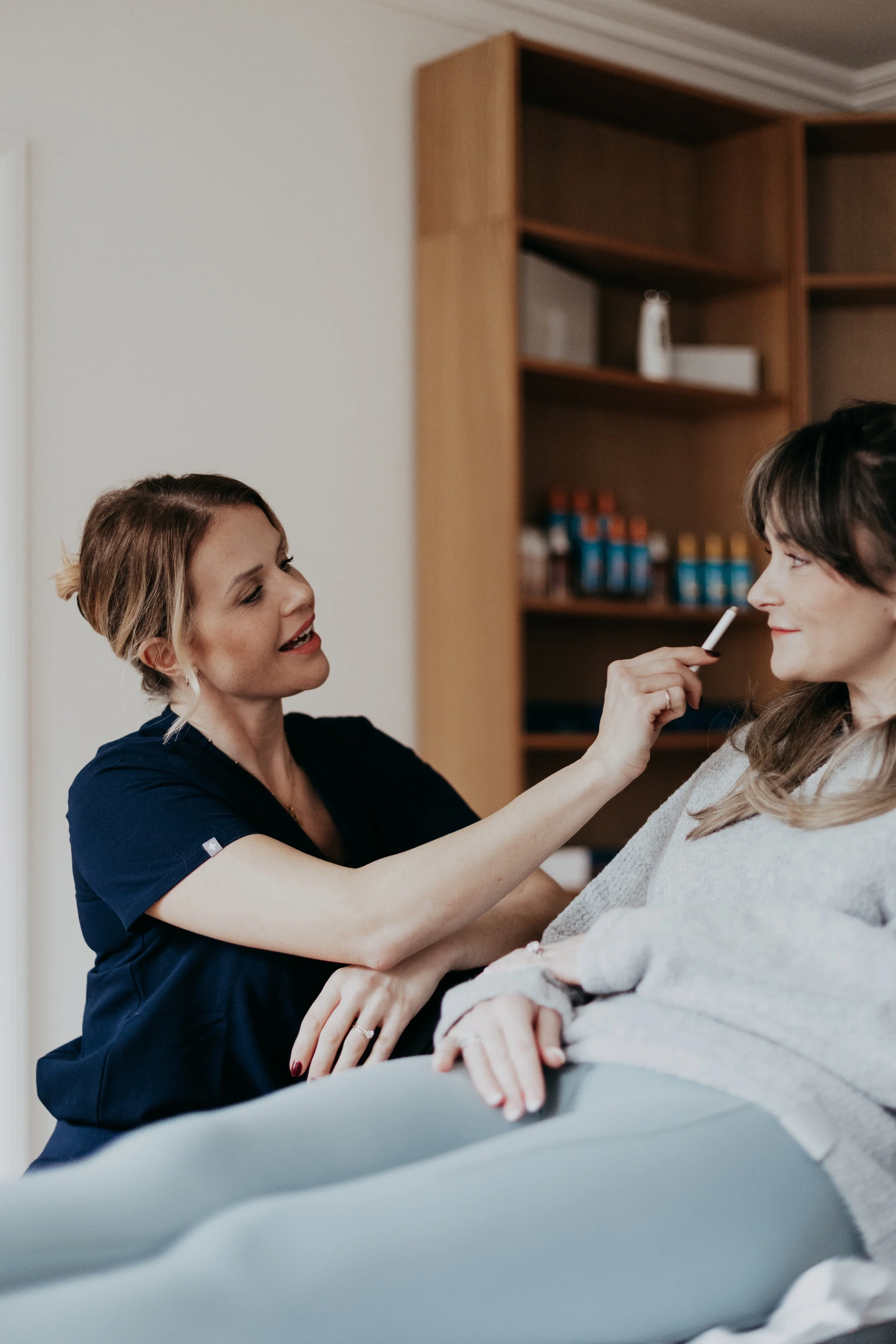 Close-up of a woman with closed eyes during a facial treatment, showing smooth skin and well-groomed eyebrows.