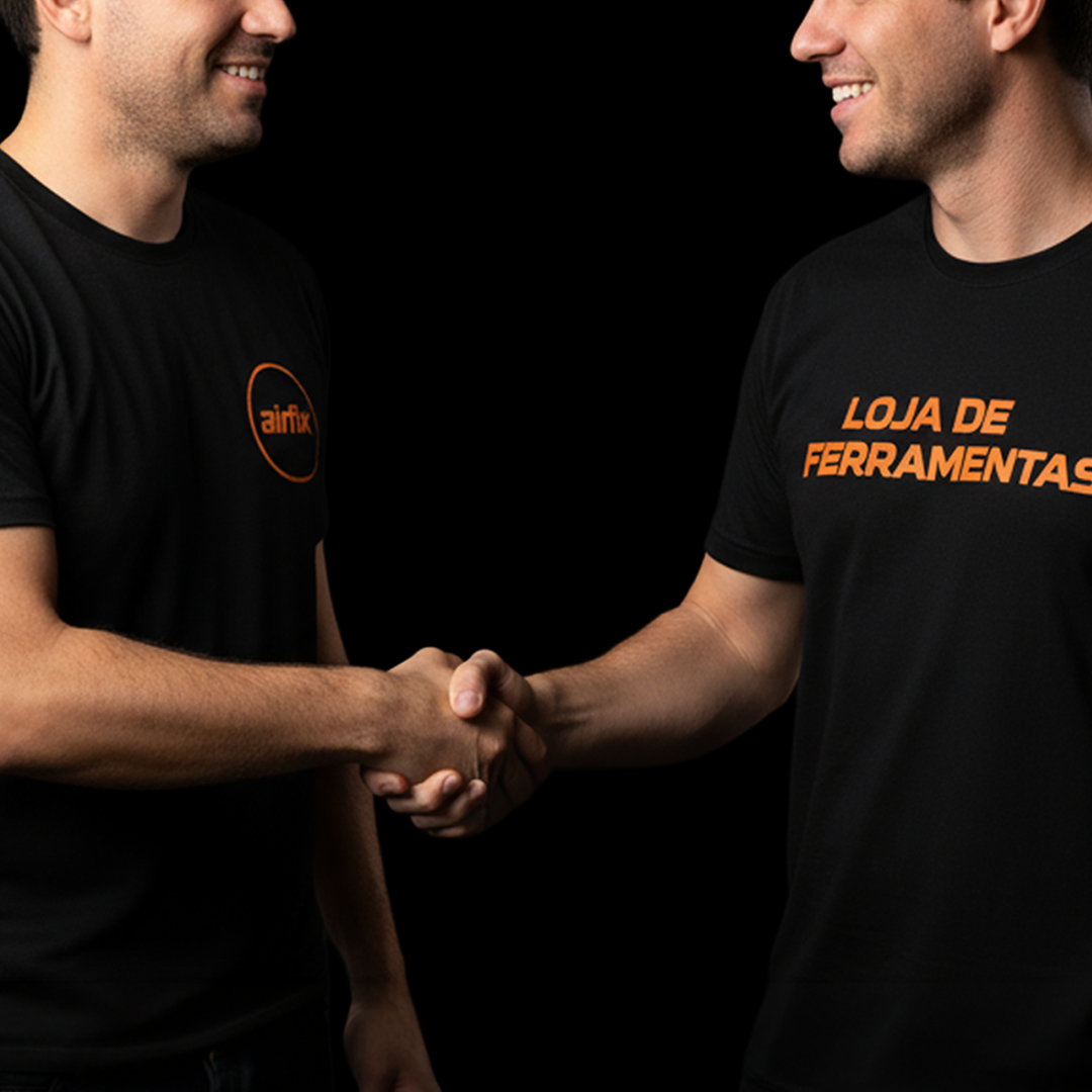 Duas pessoas apertando as mãos, vestindo camisetas pretas, uma com o logo 'airfix' e outra com a frase 'LOJA DE FERRAMENTAS', contra fundo preto.