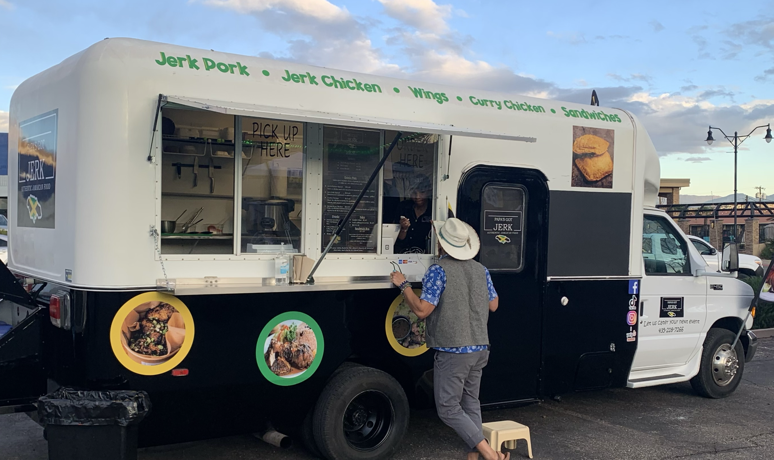 Food truck selling jerk chicken, jerk pork, wings, curry chicken, and sandwiches with a customer placing an order.