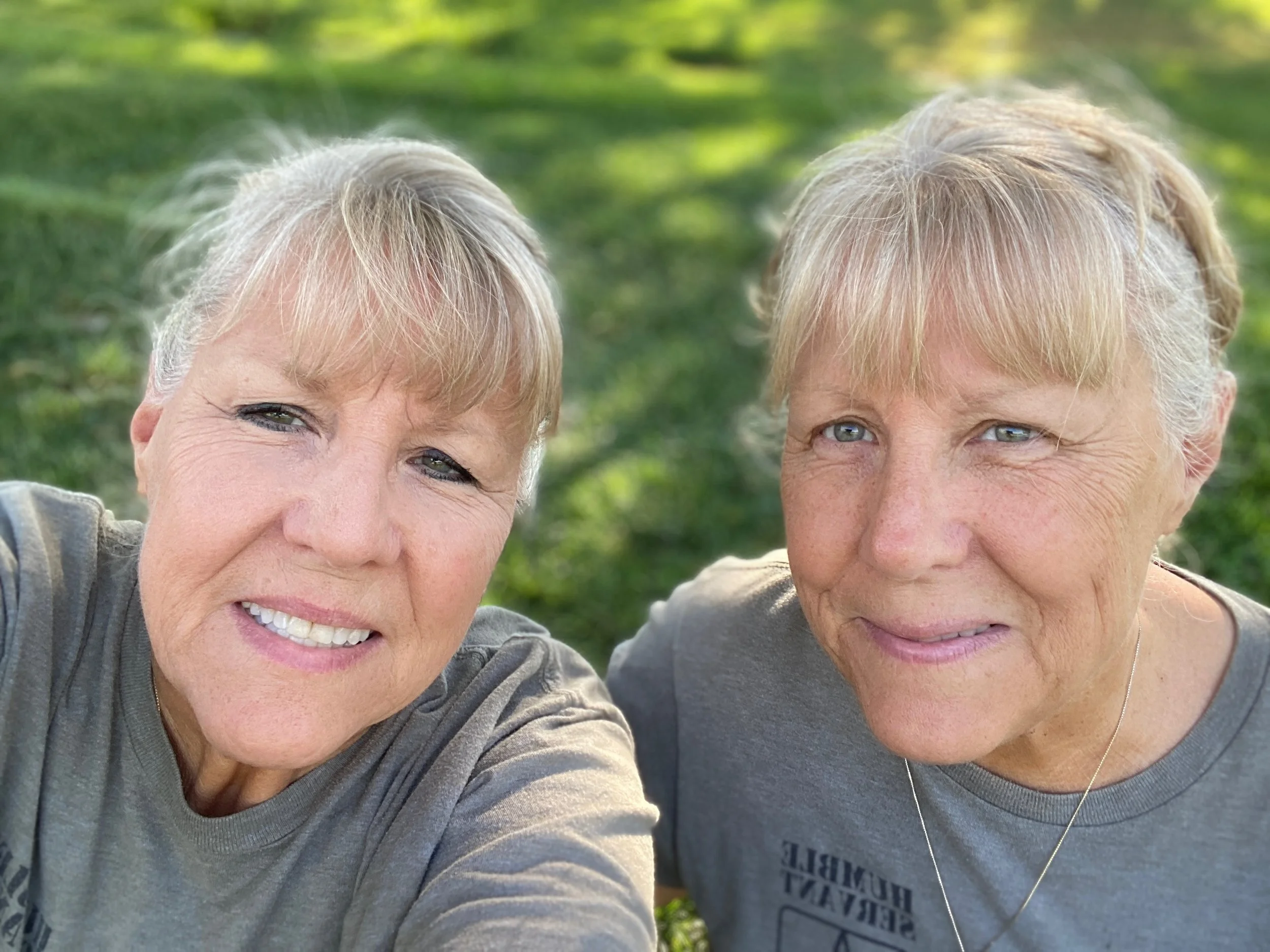 Smiling women wearing sunglasses standing outdoors on a sunny day.