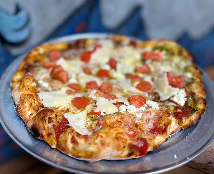 Cheese pizza with tomato, cheese, and basil toppings on a metal tray
