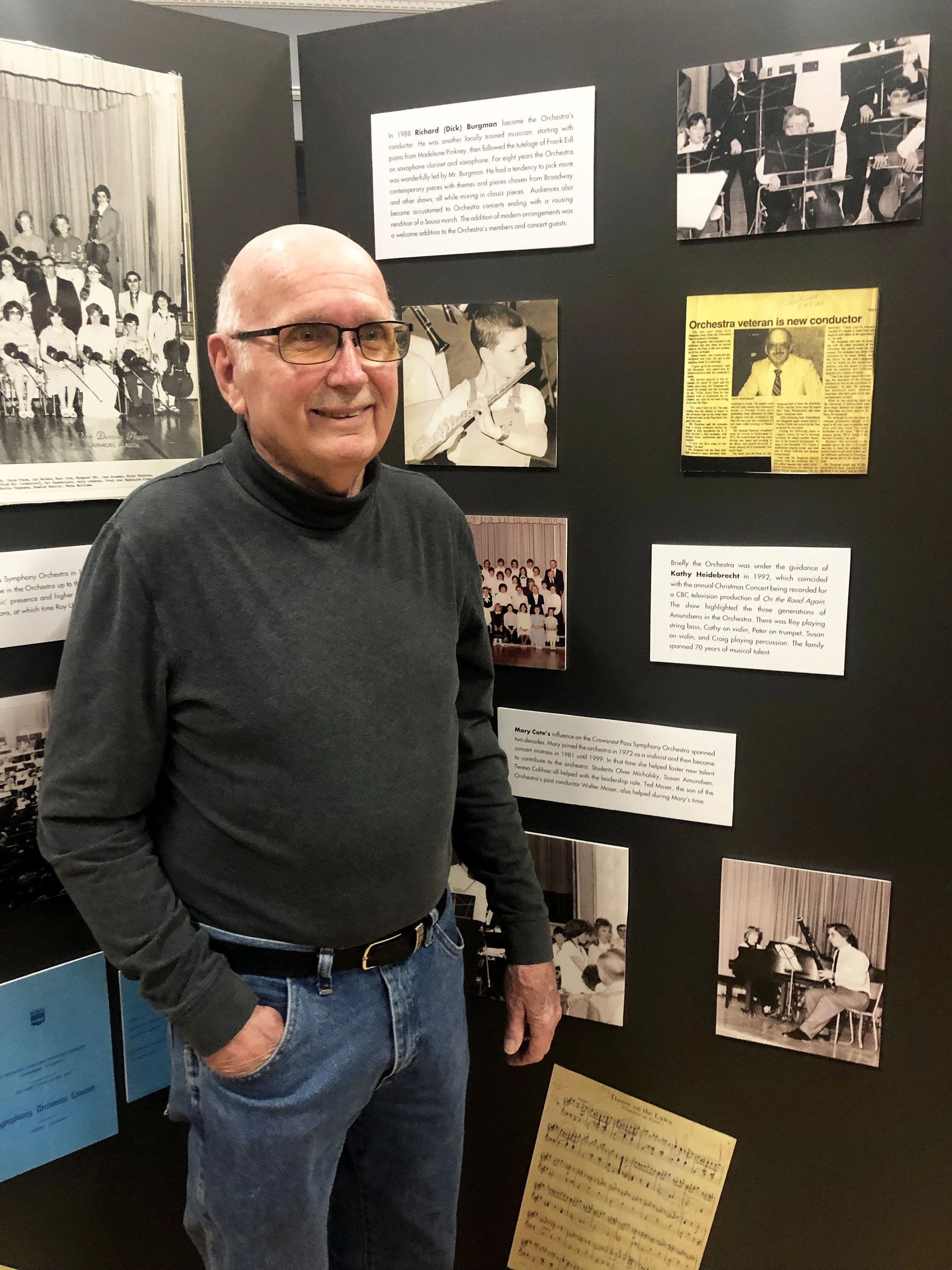 Former conductor Dick Burgman, who led the orchestra for 8 years,  poses at one of the displays. 