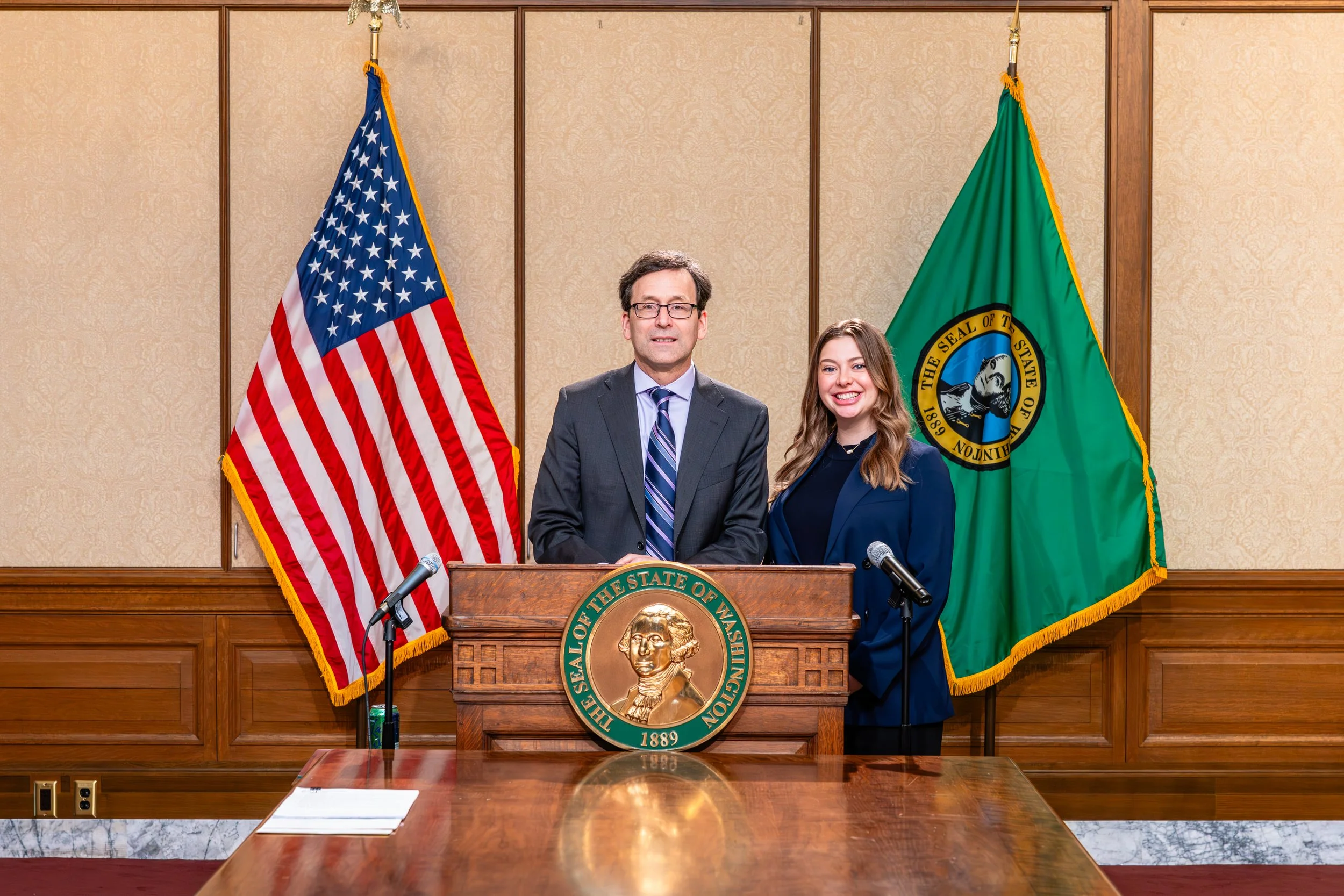 Governor Ferguson and Washington State Lobbyist/Government Affairs expert, Abbey Smelcer, at the signing of senate bill 6226. They stand at a podium with the Washington State Seal on it. Photo taken in Olympia, Washington in the Governor's Press room