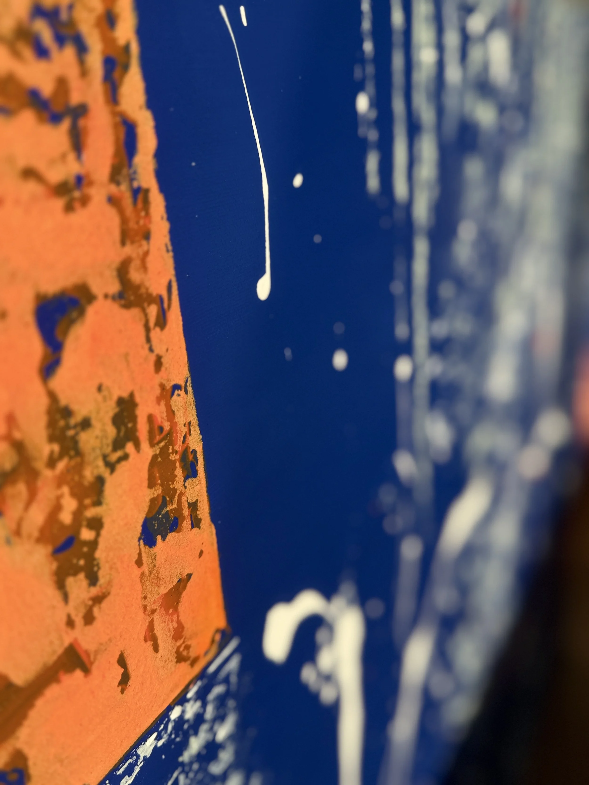 Une peinture abstraite avec des taches d'orange, de bleu et de blanc.