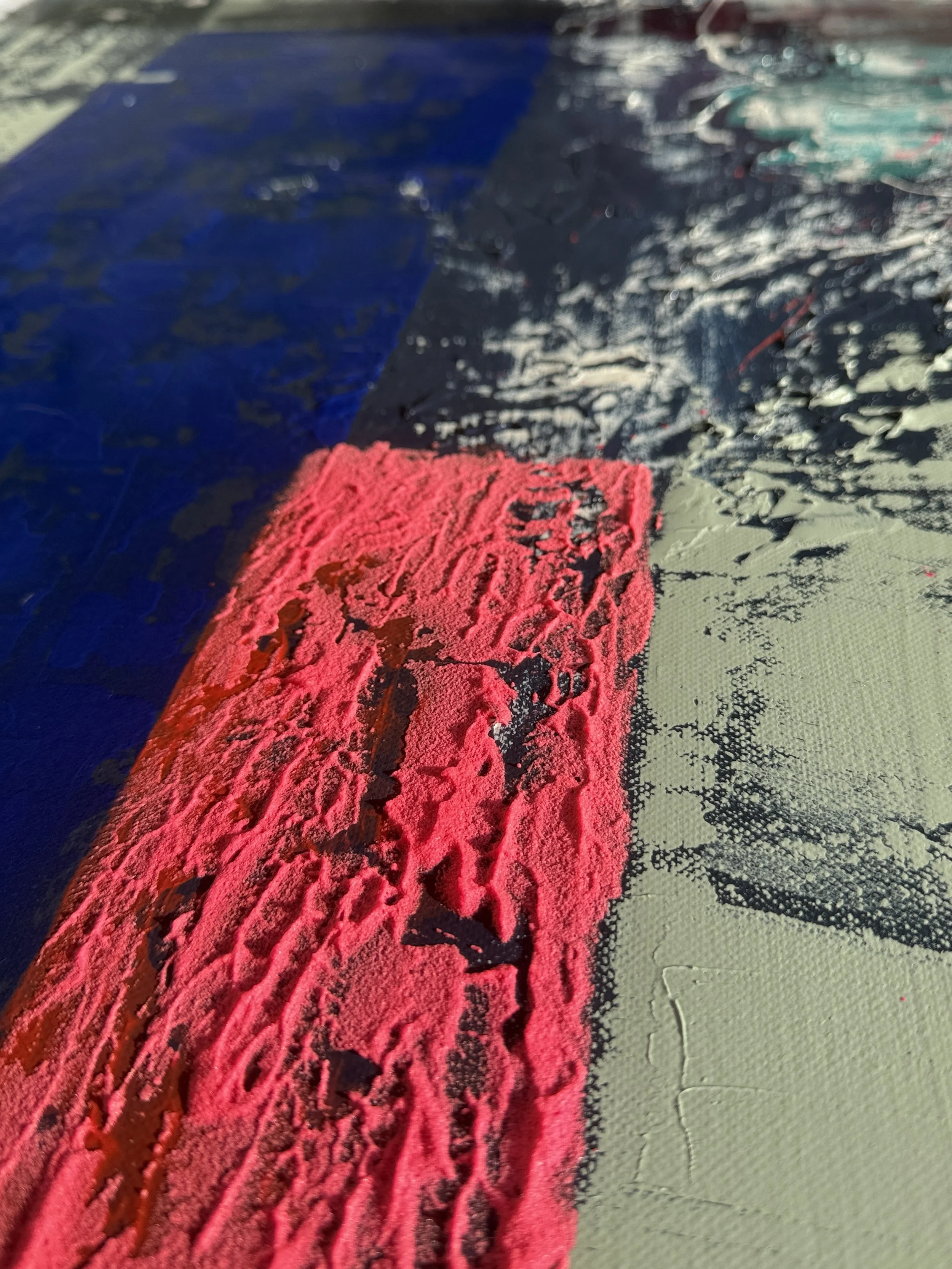 Ceci est une photo en gros plan d'une peinture en cours de réalisation avec des couleurs vives, y compris du rouge, du bleu, du noir et du gris, sur une toile.