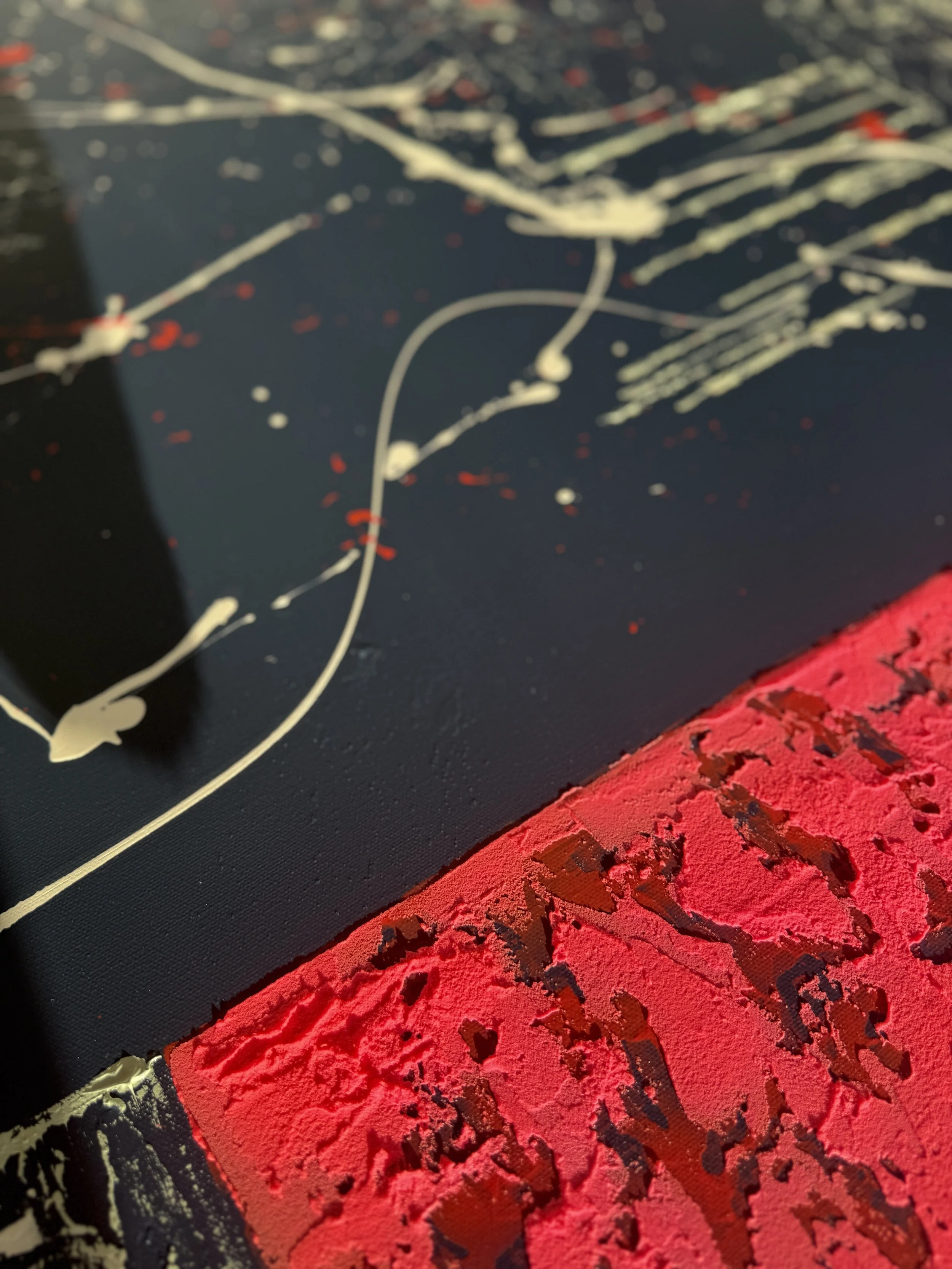 Détail d'une œuvre d'art abstraite avec des couleurs rouge, noir, blanc et beige. Texture visible avec éclats de peinture et lignes fluides.