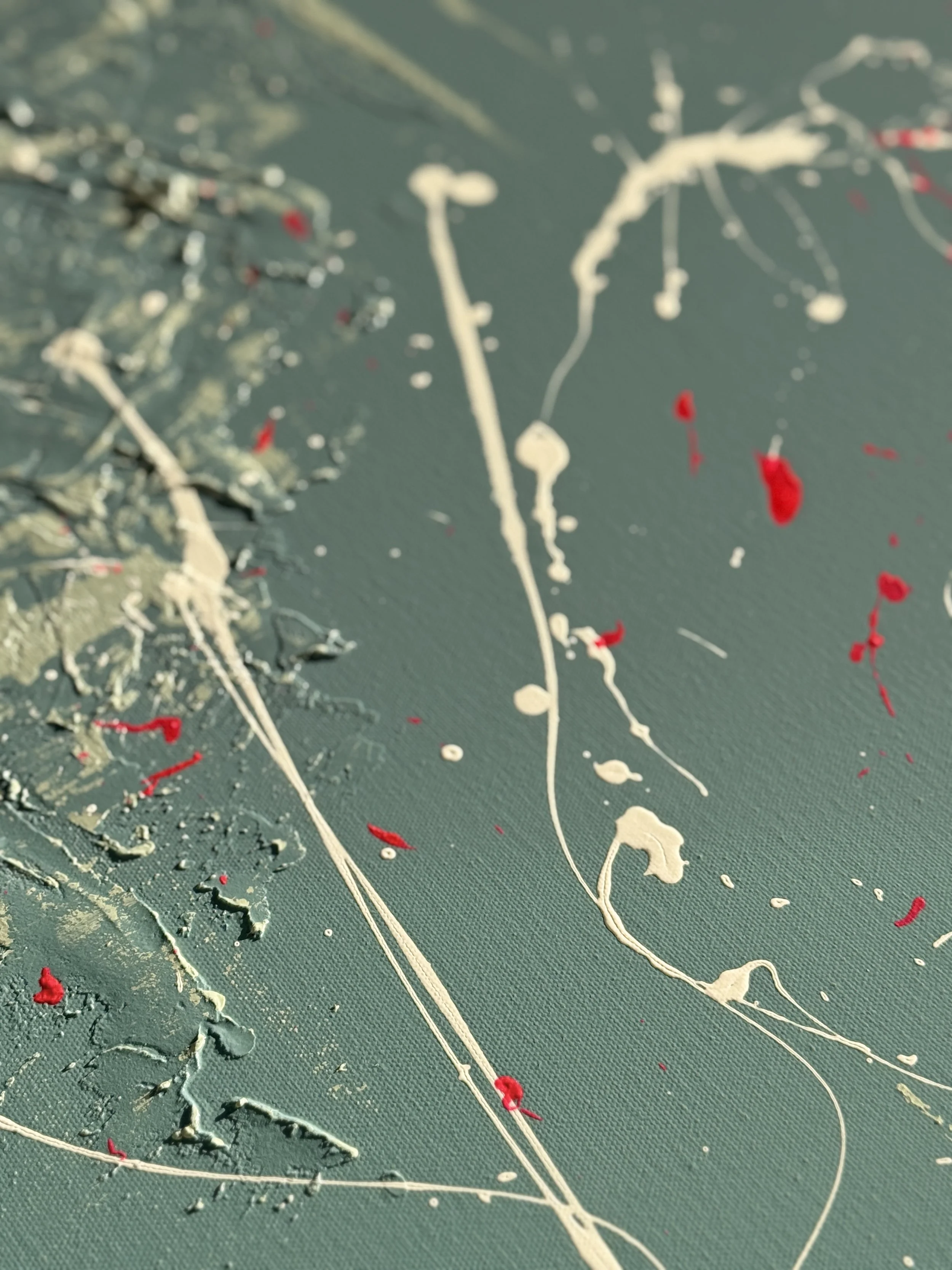 Une toile avec des éclaboussures de peinture blanche et rouge sur un fond vert.