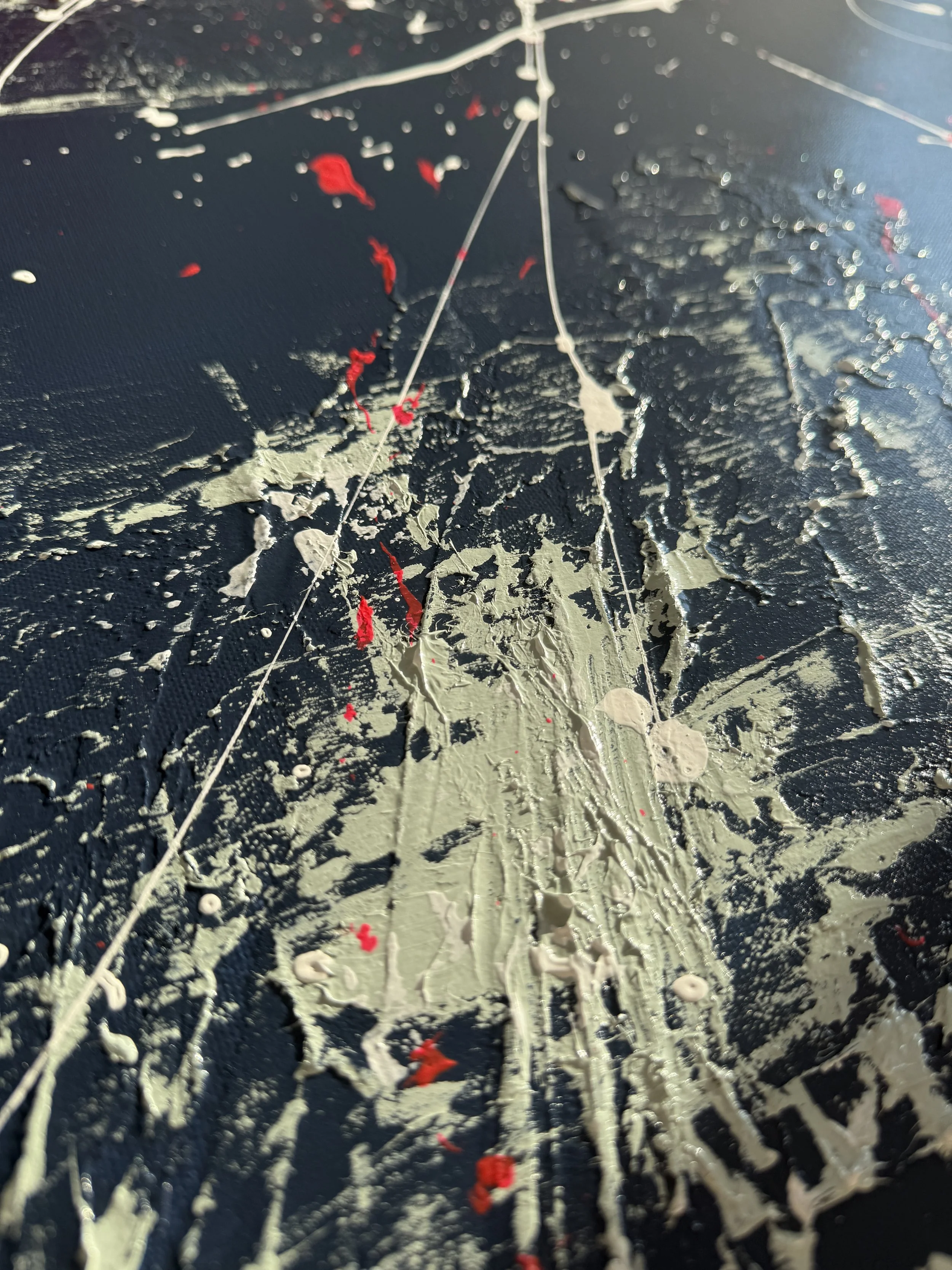 Peinture abstraite avec des éclaboussures de peinture beige, blanche et rouge sur un fond noir.