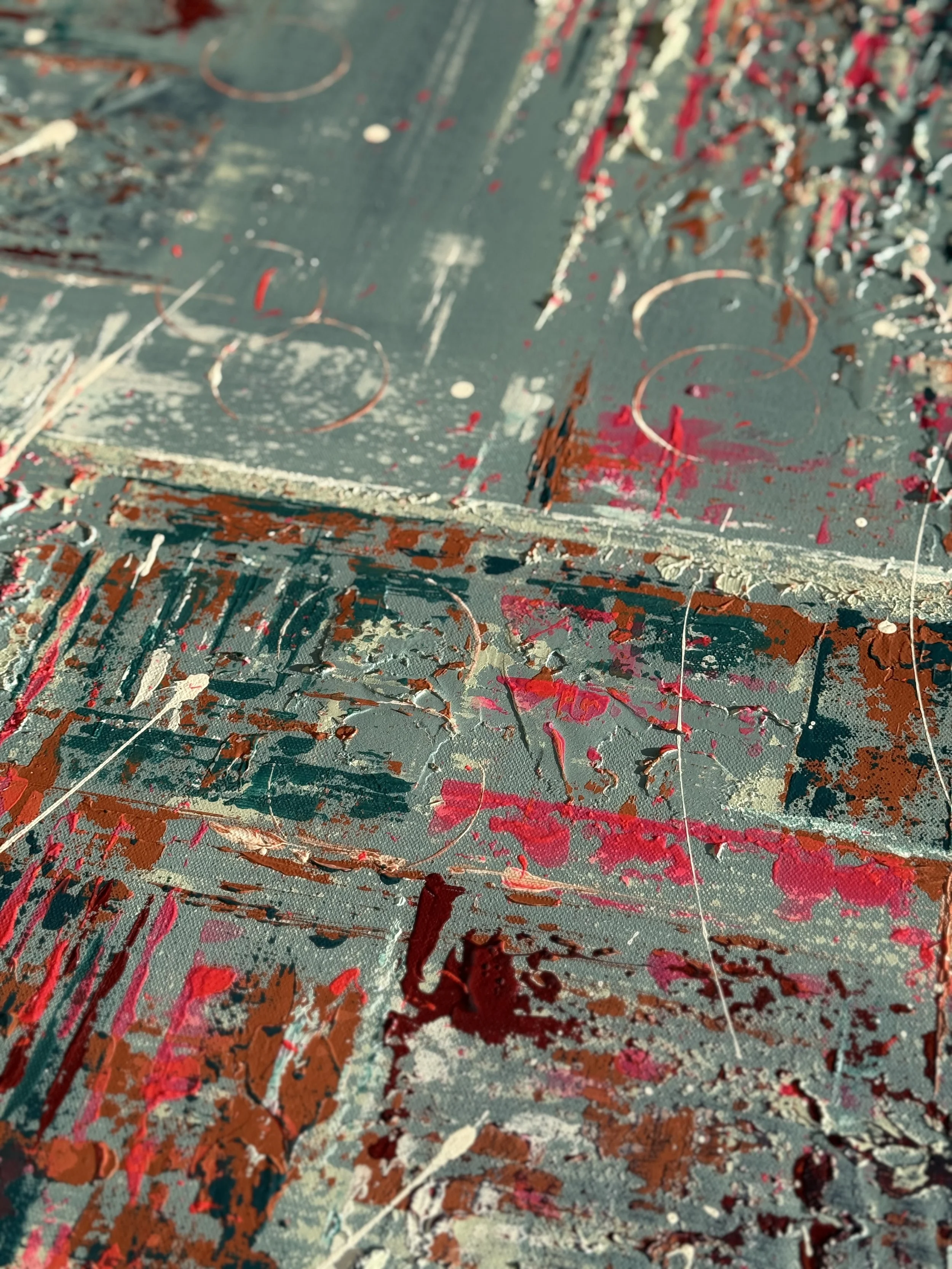 Table de travail avec des traces de peinture de différentes couleurs, notamment rouge, blanc et marron, sur une surface en bois.