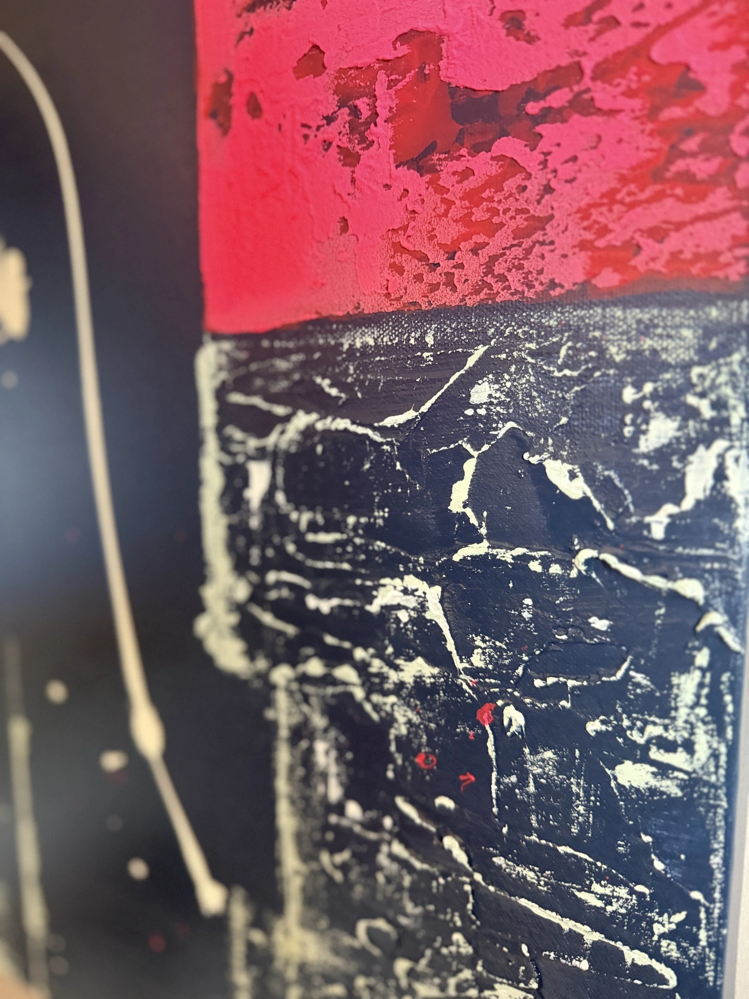 Peinture abstraite avec des textures en rouge, noir, blanc et des éclaboussures. Les couleurs et textures créent un contraste visuel.