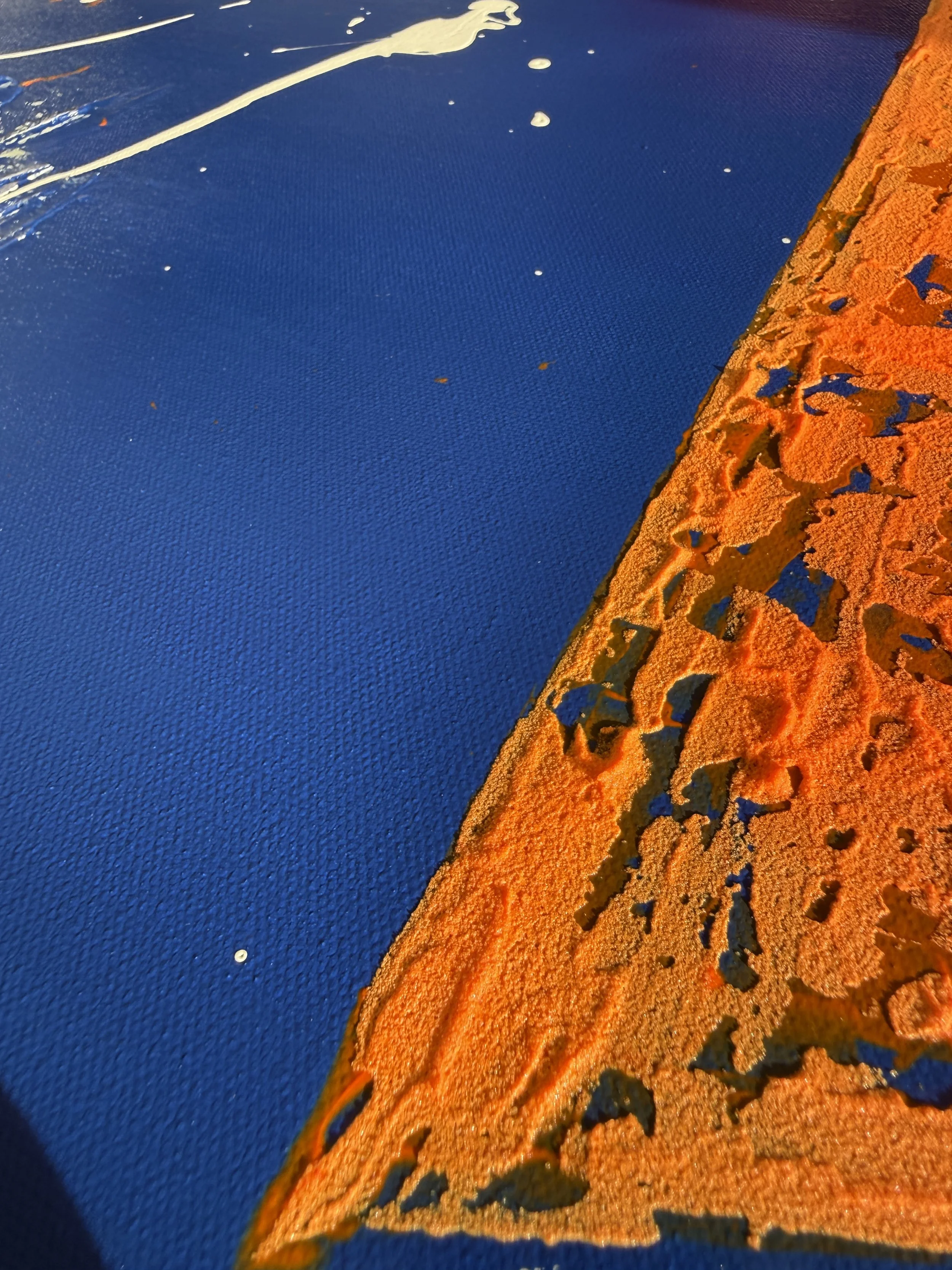 Détail de deux surfaces en contact, l'une orange avec des motifs découpés et l'autre bleue avec une texture en relief.