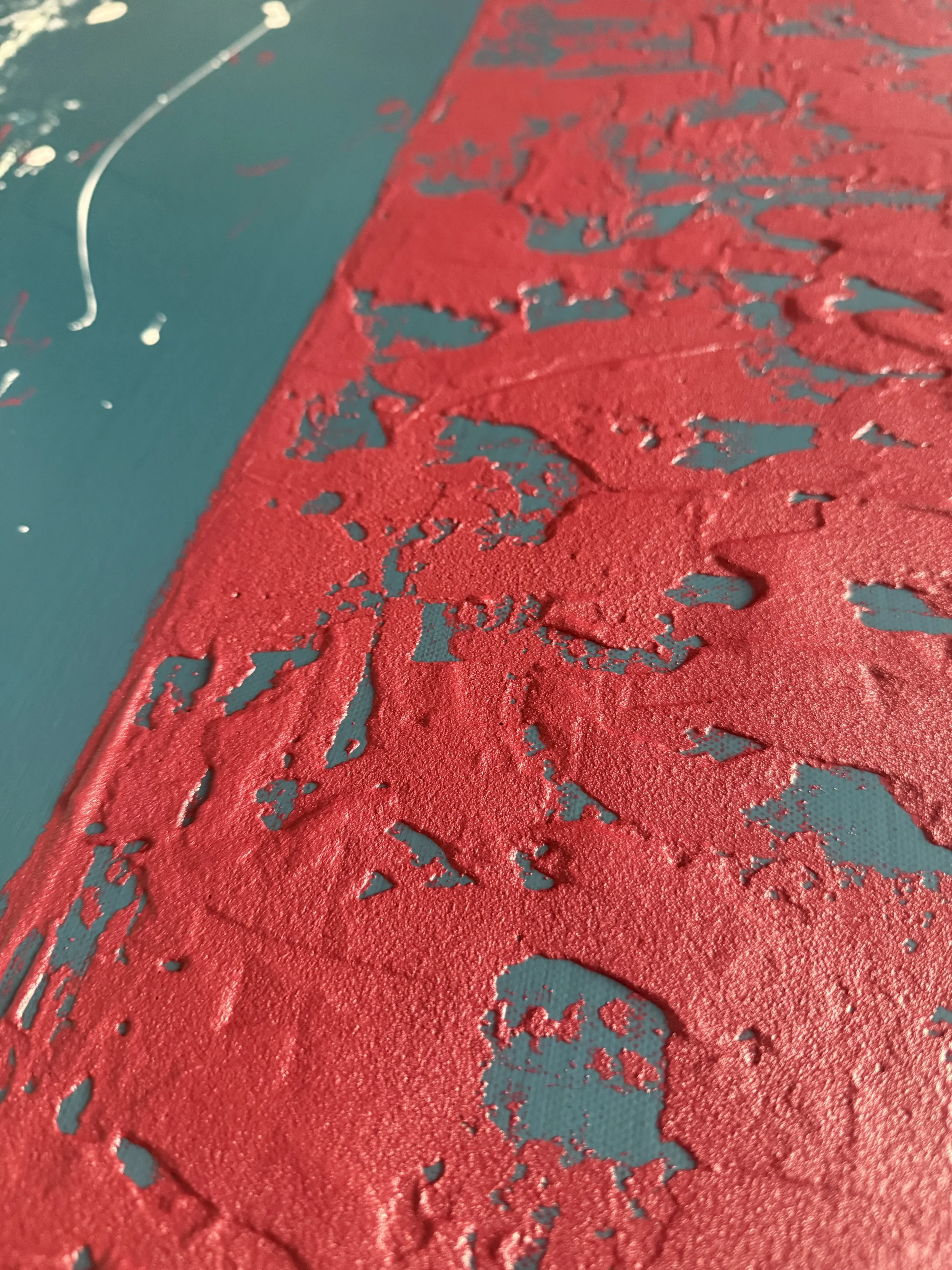 Une surface en peinture rouge avec des zones craquelées sur un fond bleu.