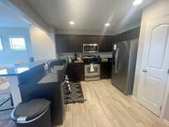 Modern kitchen with dark cabinets, stainless steel appliances, and a breakfast bar.