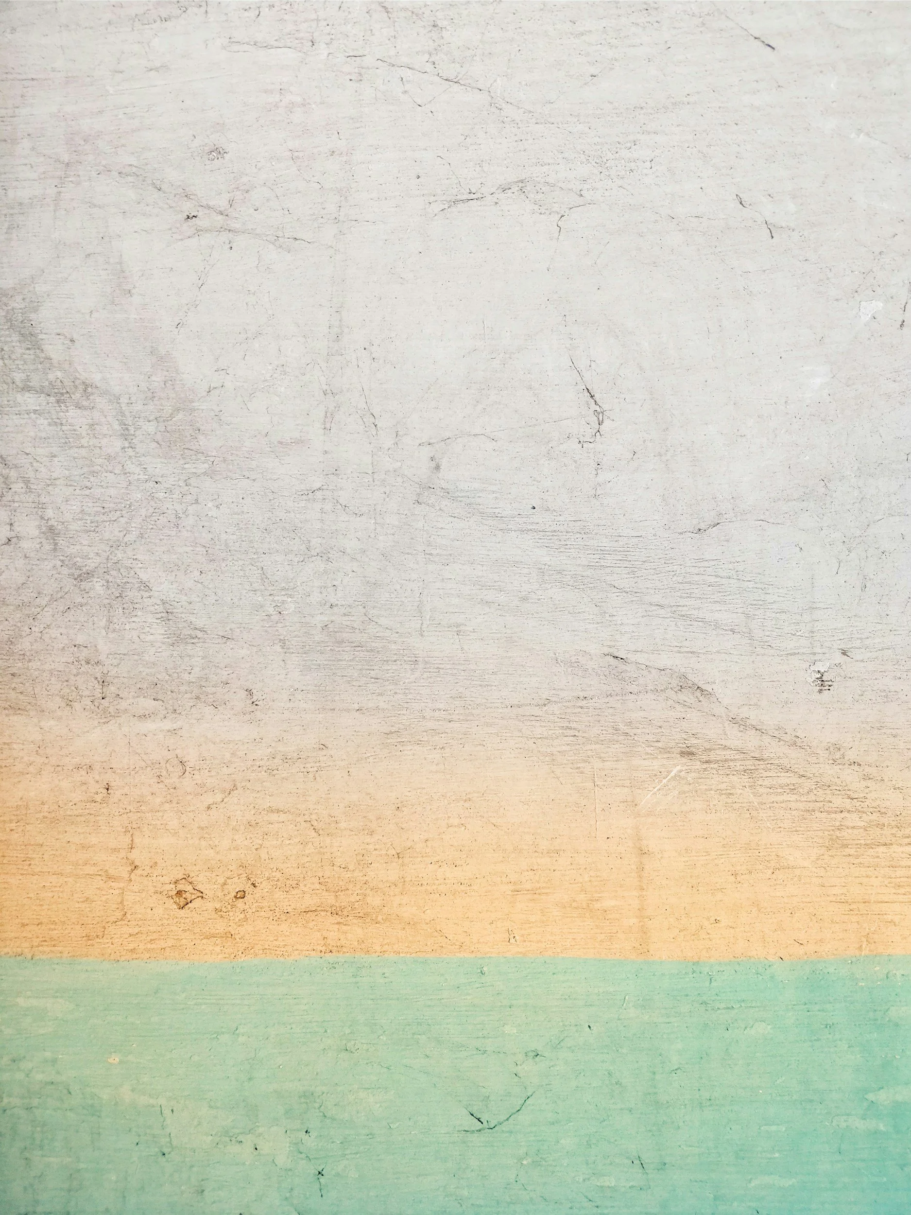 Photo d'une table en bois peinte avec plusieurs couches de peinture de couleur pastel délavées, allant du blanc en haut, à des teintes beige, vert pâle, puis bleu en bas.