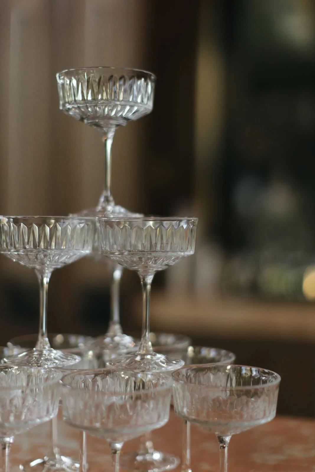 Stacked crystal cocktail glasses with patterned sides on a table.