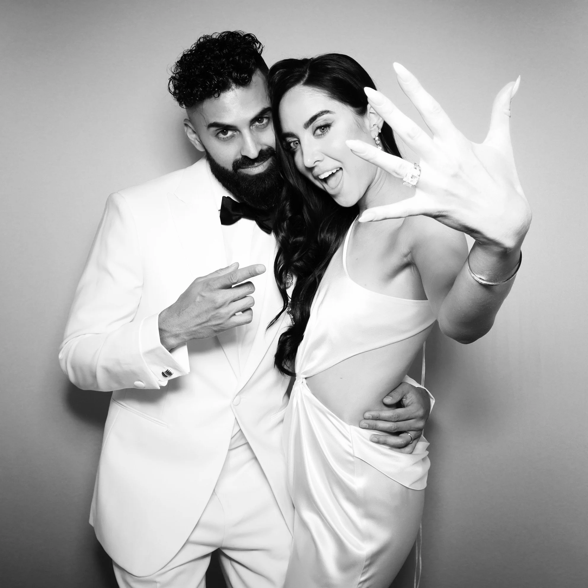 Bride and groom showing off wedding rings in a vintage style photo booth