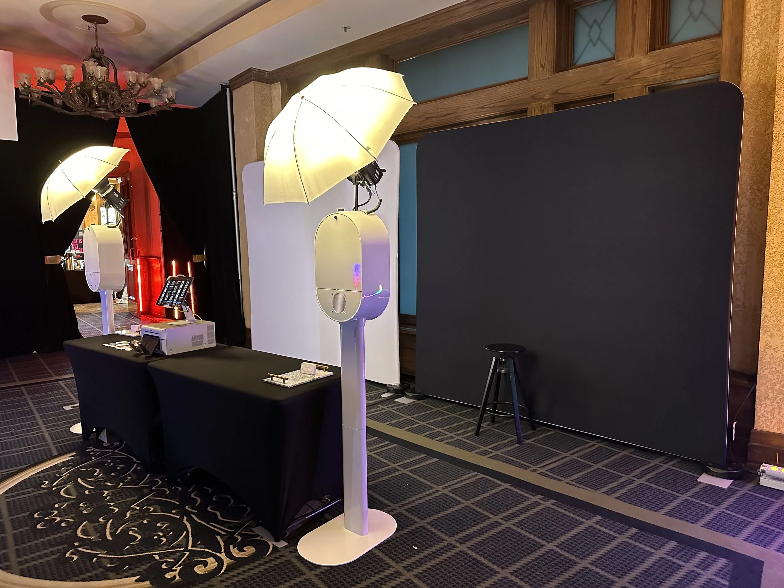 Photo of a display area with luggage scanners, umbrellas, and a black backdrop, likely at an airport or event.