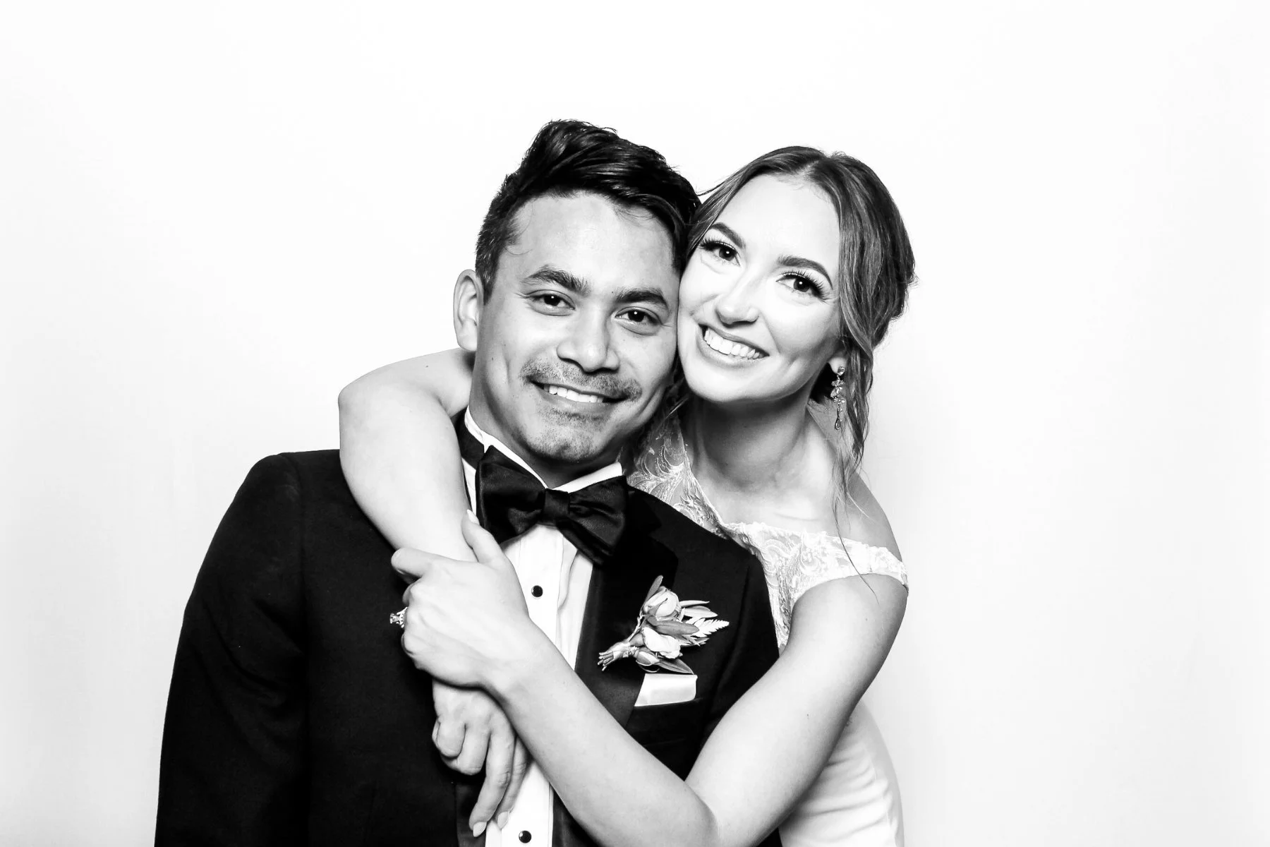 Black and white photograph of a smiling couple, the woman with her arm around the man's shoulders, both dressed for a formal occasion.