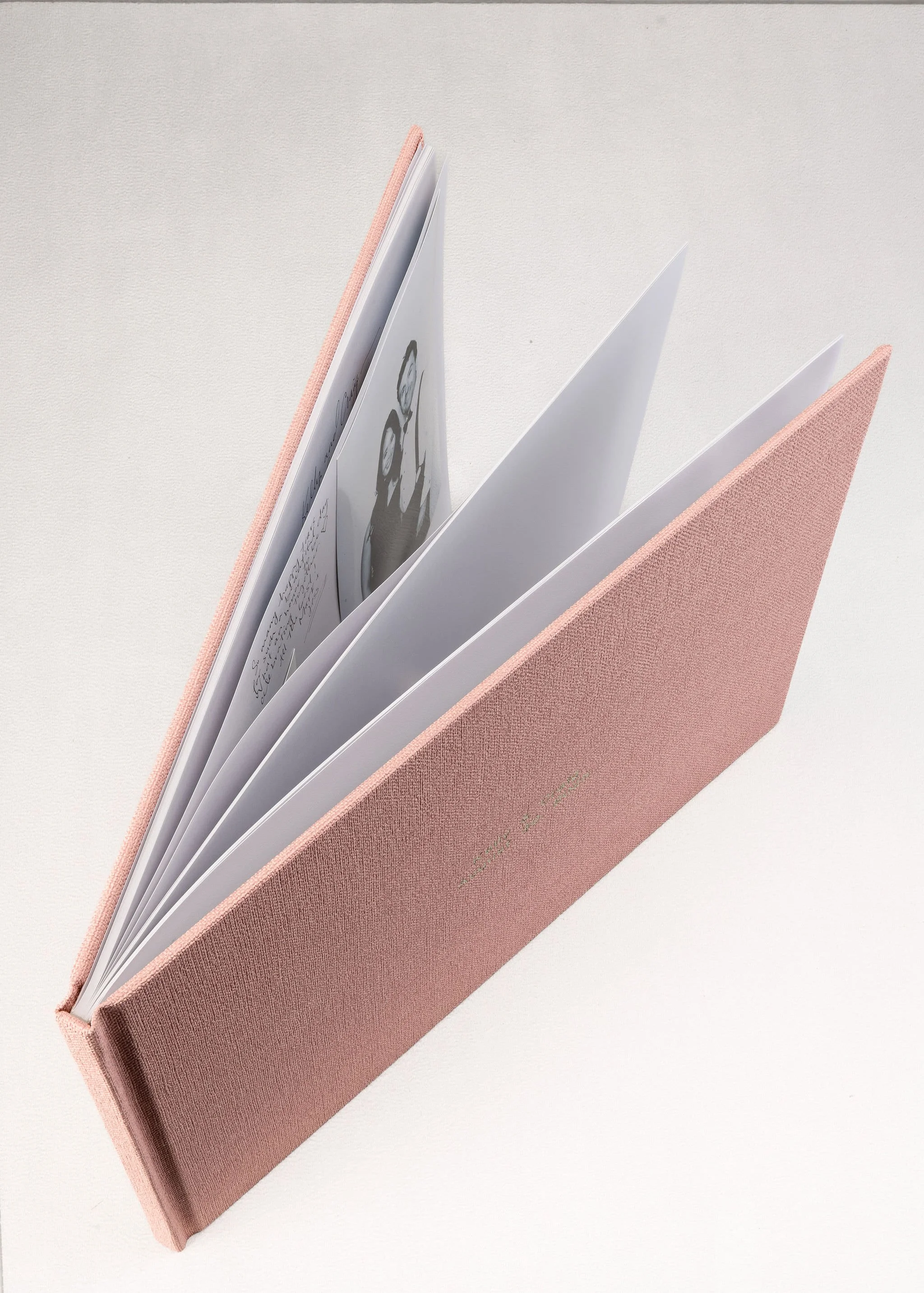 Open pink notebook with visible pages, one page has black and white photos and handwritten notes.