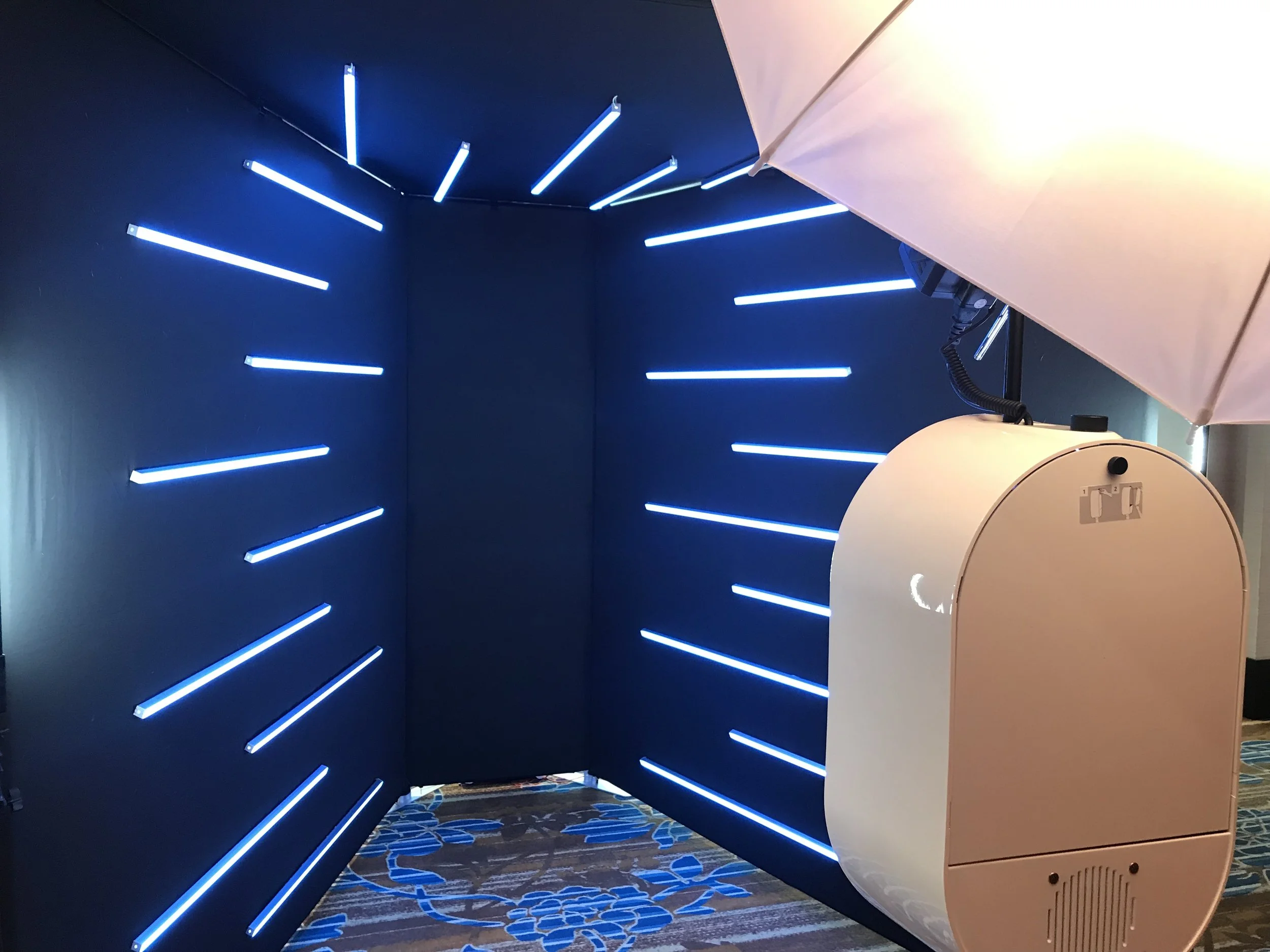 a white photo booth setup in front of an illuminated led light tunnel for a slow motion video booth