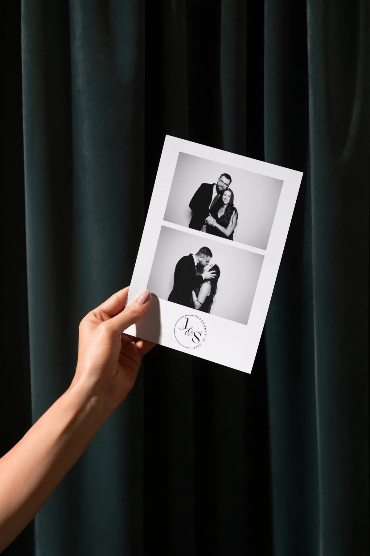 A hand holding a photo strip with black and white wedding photos of a couple, with a dark curtain in the background.