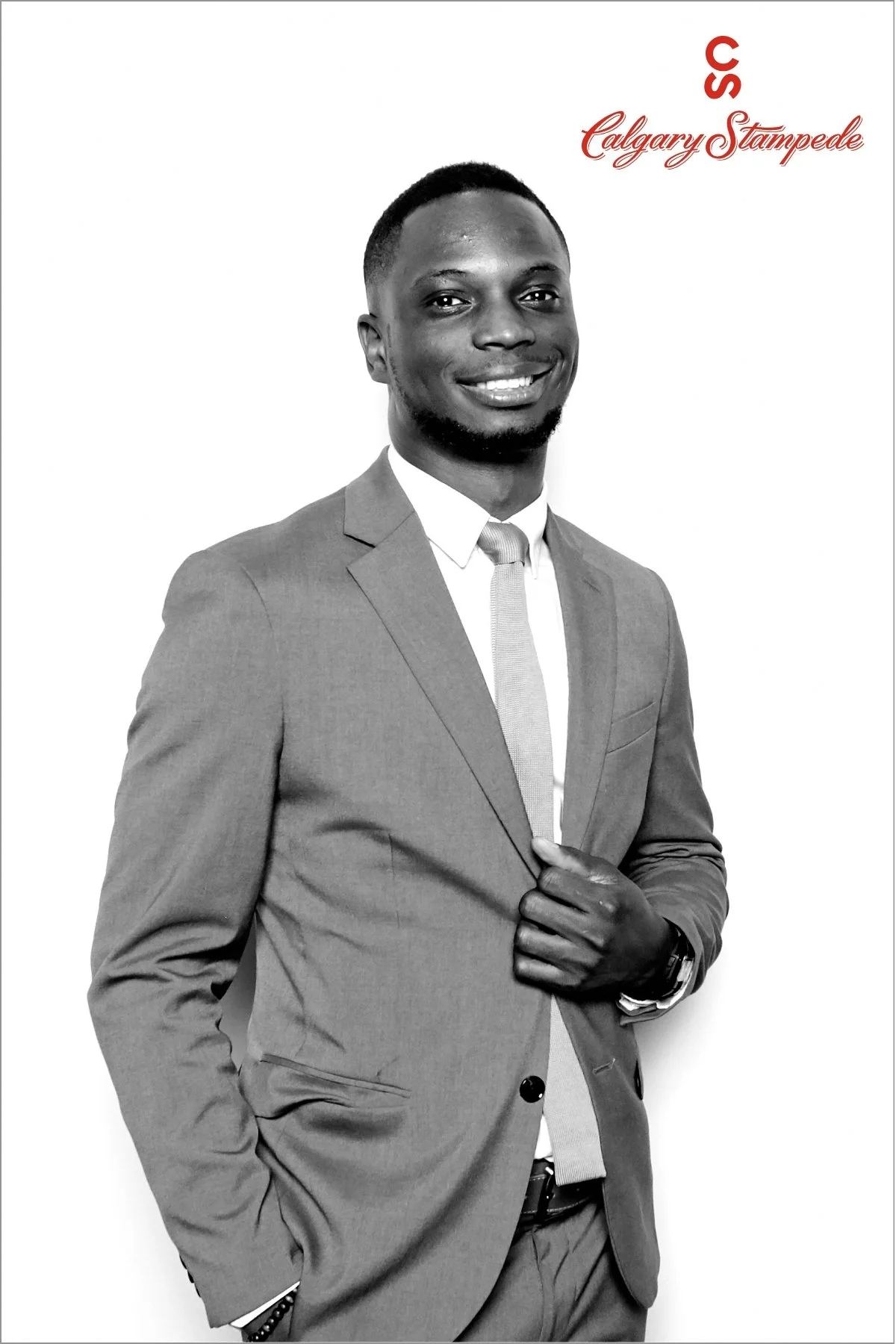 Black and white photo of a man in a suit smiling, with text in red and cursive reading 'Calgary Stampede' and 'SS' in uppercase letters.