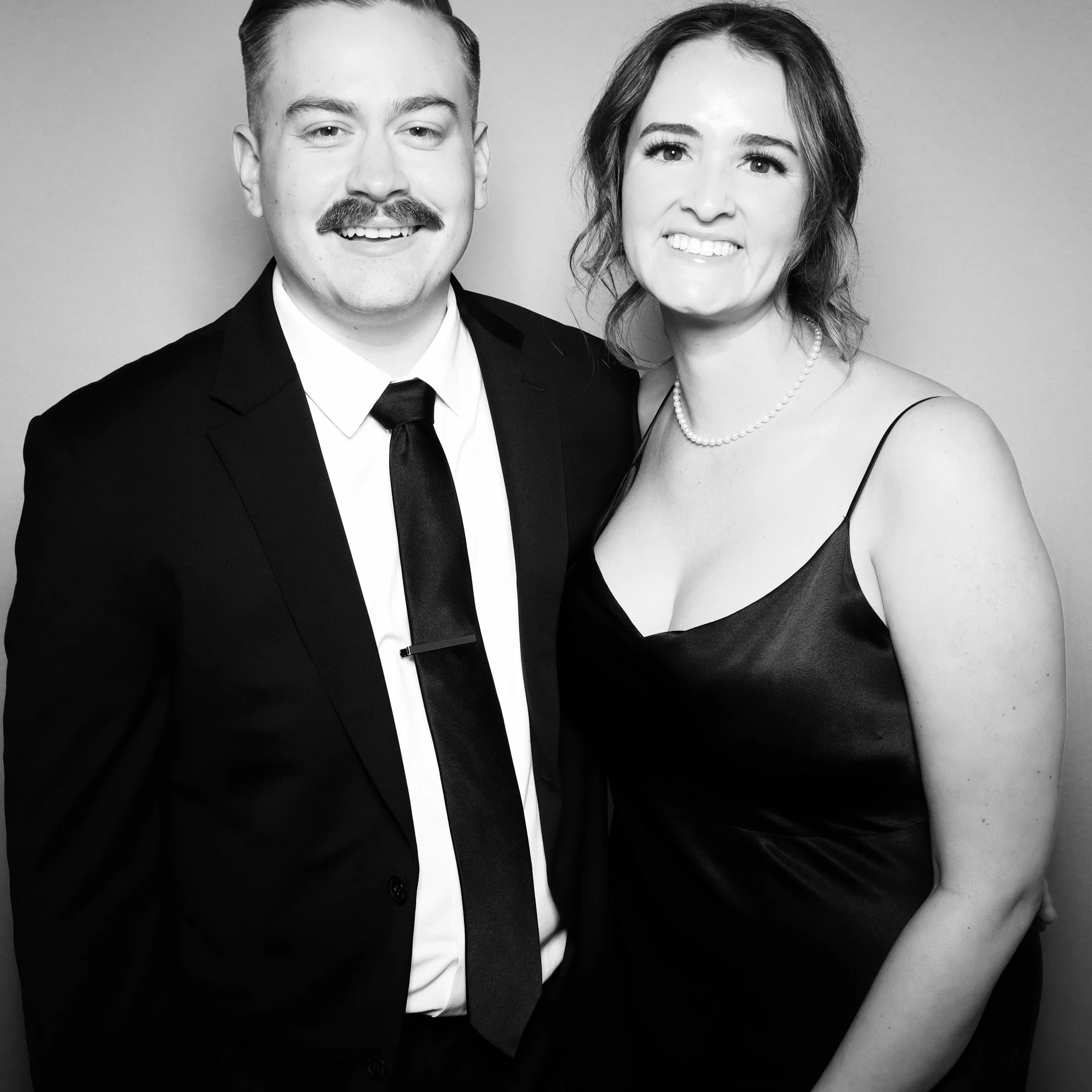 A black-and-white photo of a man in a suit and a woman in a dress smiling together.