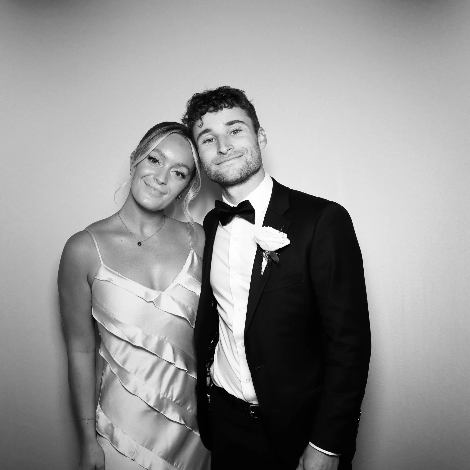Black and white photo of a happy couple dressed in formal wedding attire, standing close together and smiling.