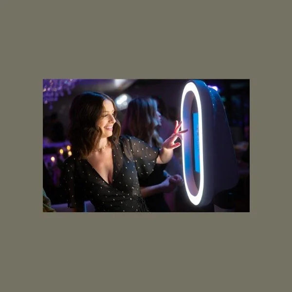 a woman tapping the screen of a digital photo booth with a going led ring light